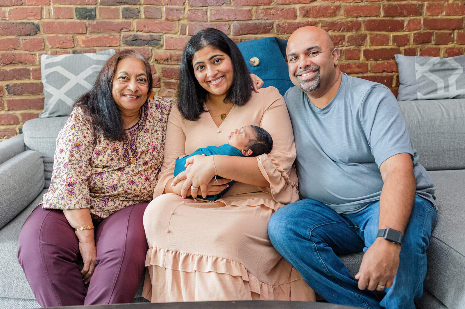 A NOVA couple holding their newborn son with grandma next to them on the couch.