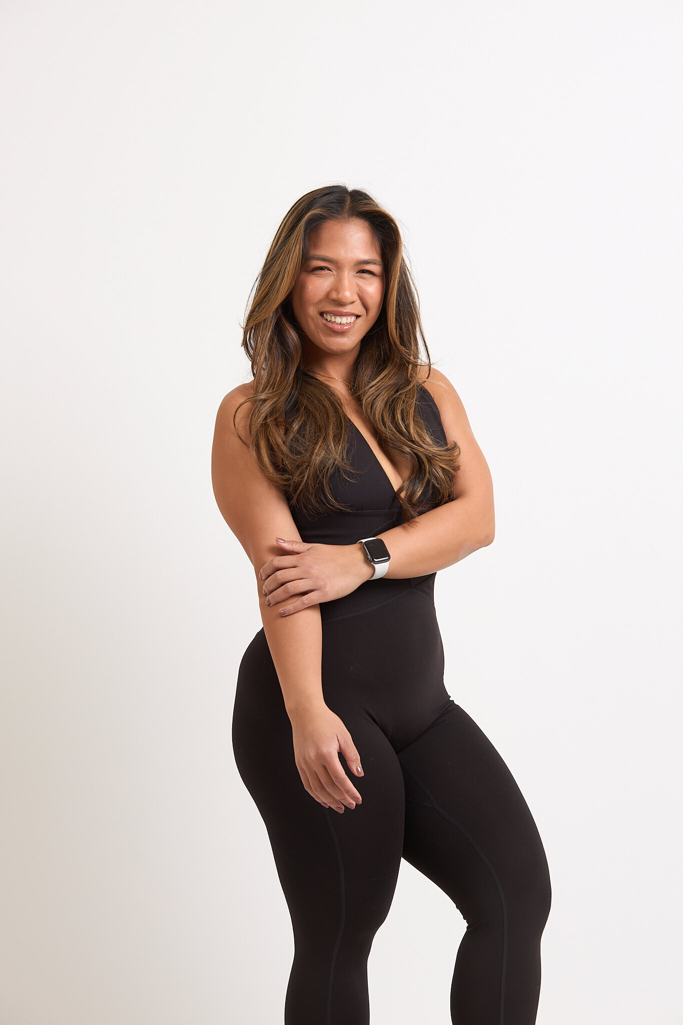 A member in black activewear standing against a pale studio wall