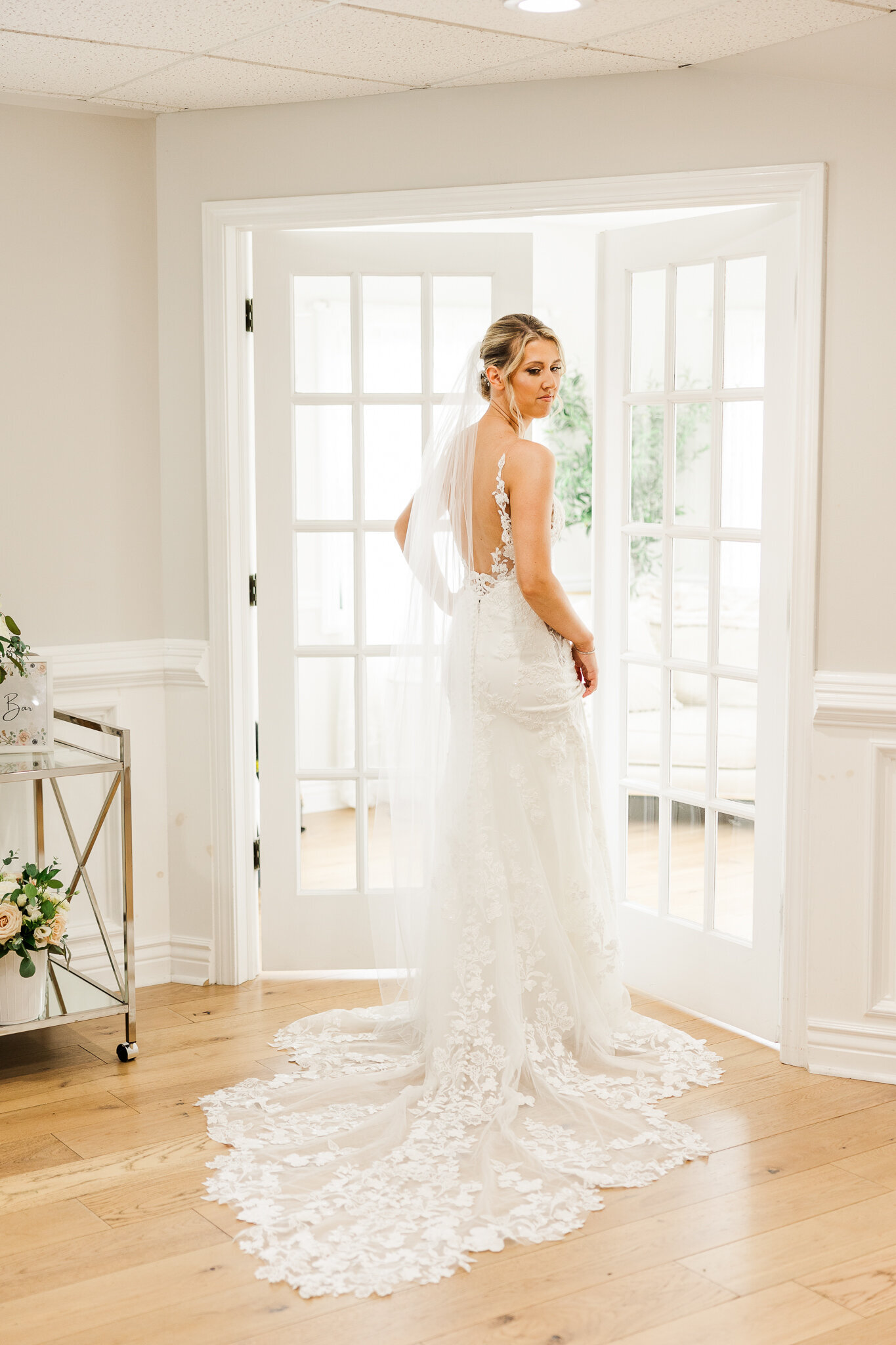 Elegant bridal portrait near glass doors in the bridal suite at SkyView Golf Club in Sparta, New Jersey