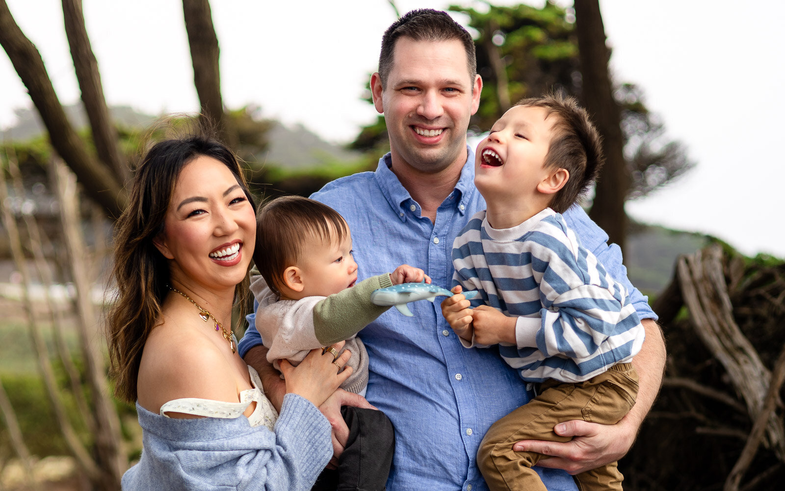 Laughing family of four during outdoor session near the woods captured by Family Photographer Ellobelle Photography