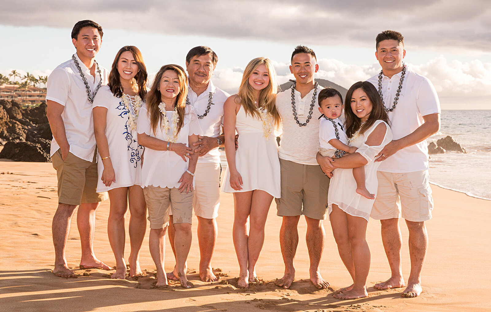 Family portrait of nine all wearing white on a beach in Oahu