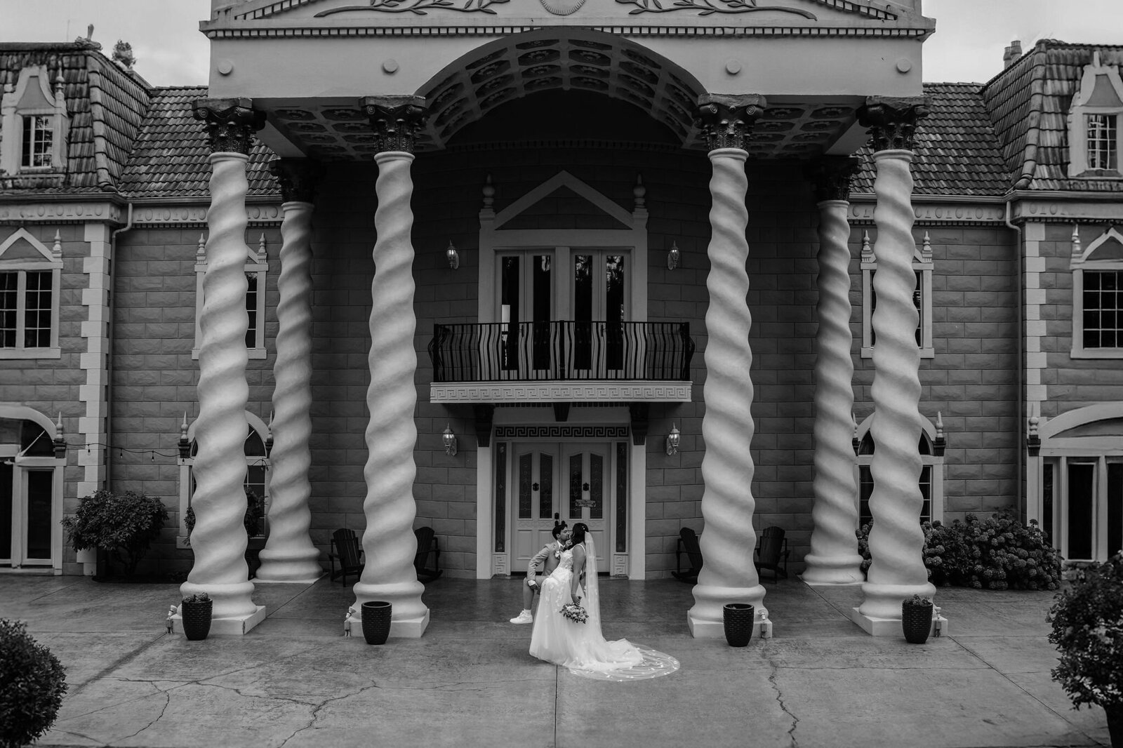 Bride is dipped by groom in front of Empress Estate in a stunning black and white photo taken by a Portland Oregon wedding photographer.