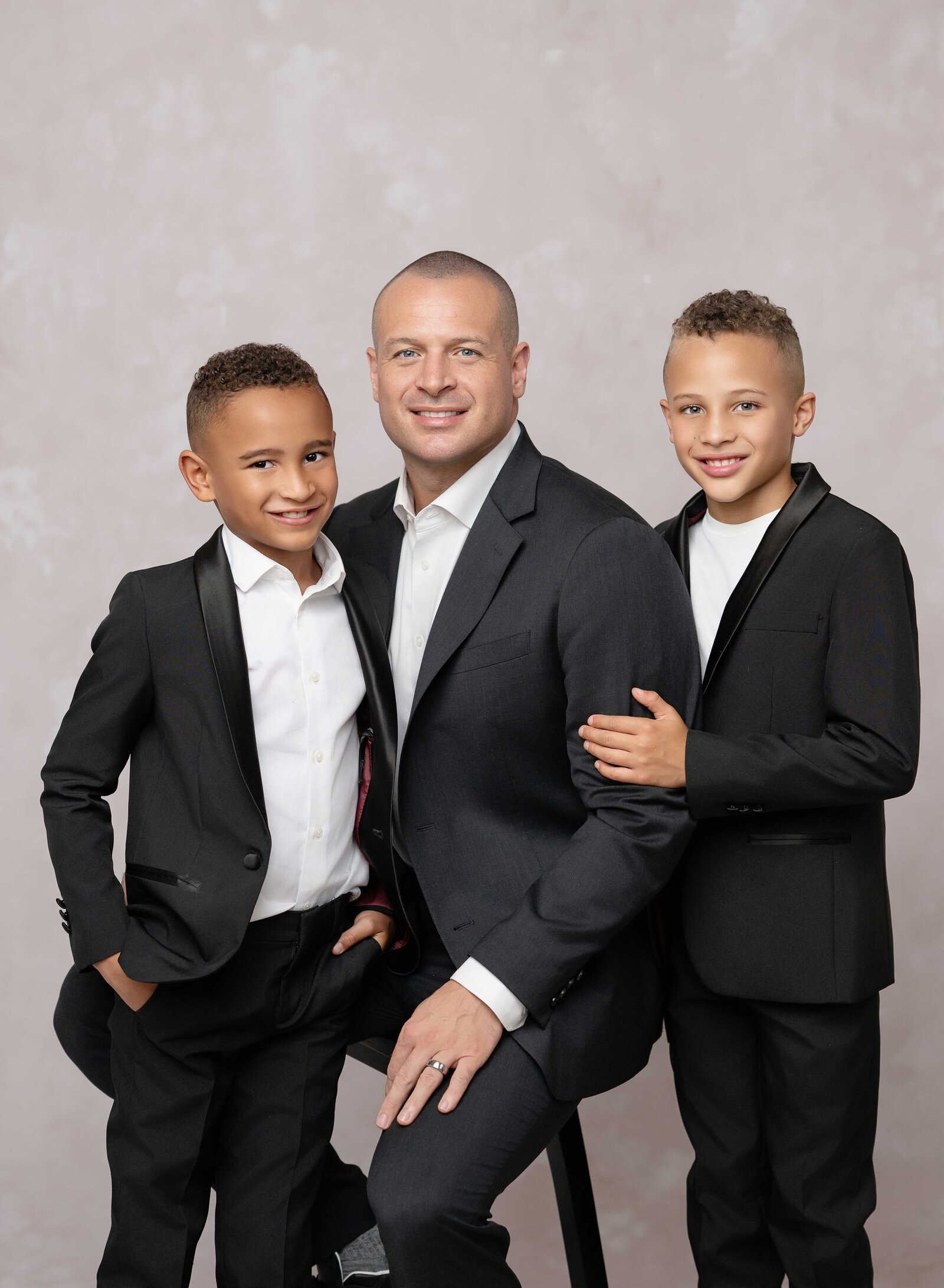 Dad on stool with son on each side posing for photo. Family photo taken by Jenni Nikki Photography at Atlanta photography studio.