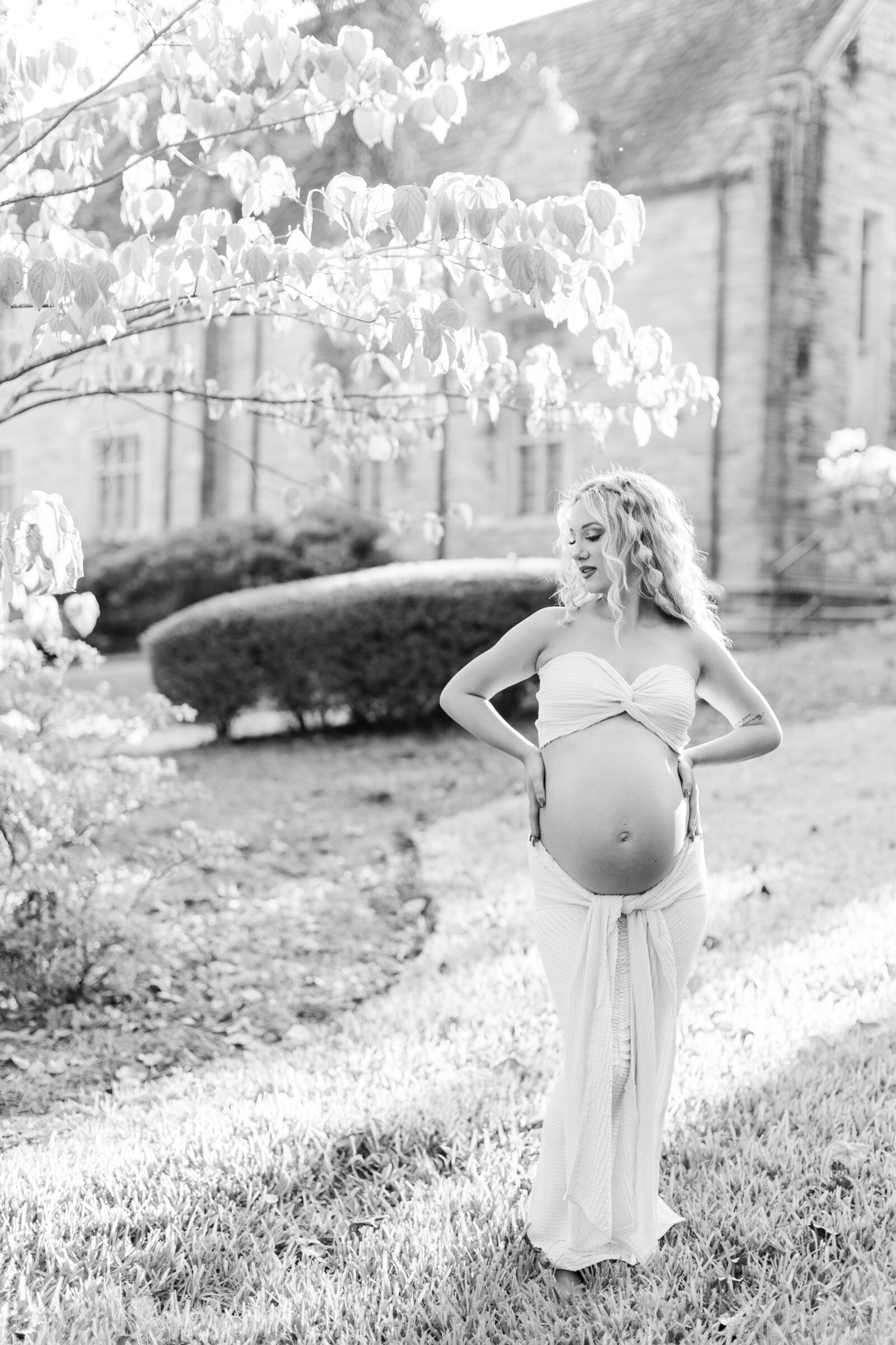 Black and white maternity portrait of Cassidy in a serene garden setting, captured by Abby Bell Photography.