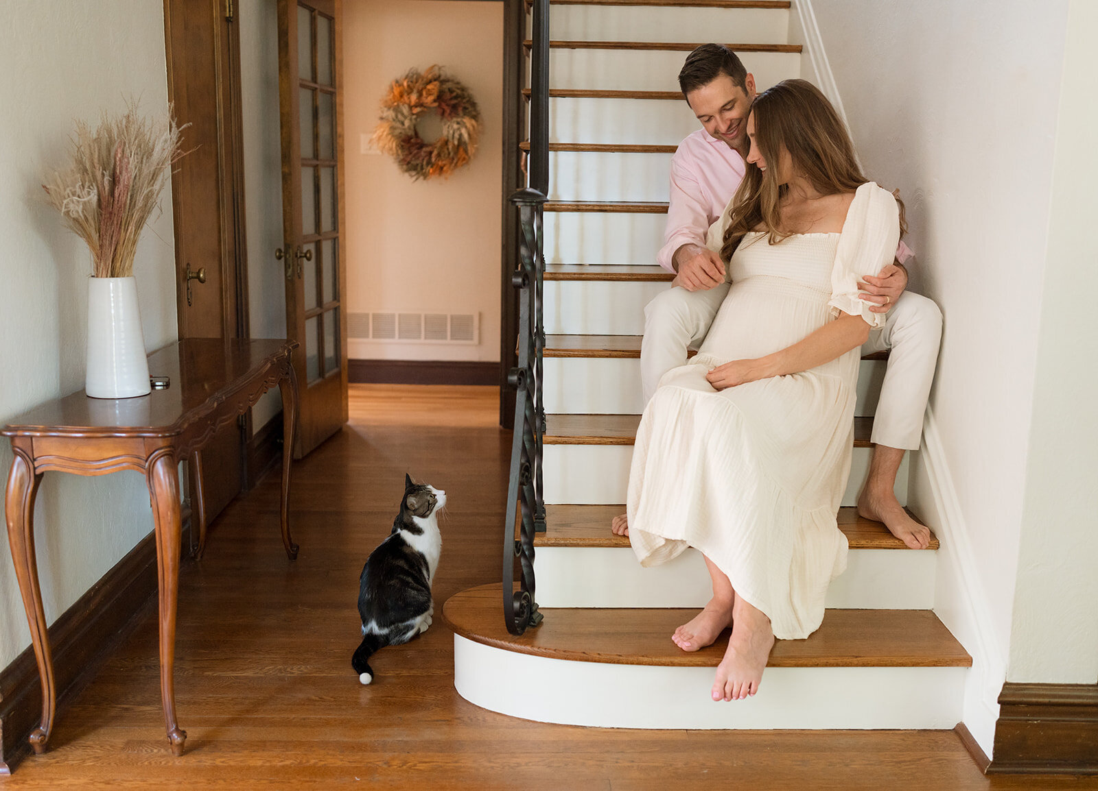 couple sitting a staricase looking at cat