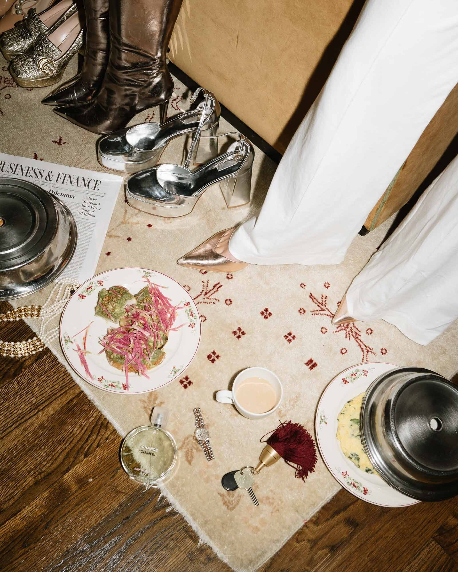 Assorted newspapers, jewelry, shoes and room service spread out on the floor of The Bowery Penthouse showcasing the life of a Salesgirl. 