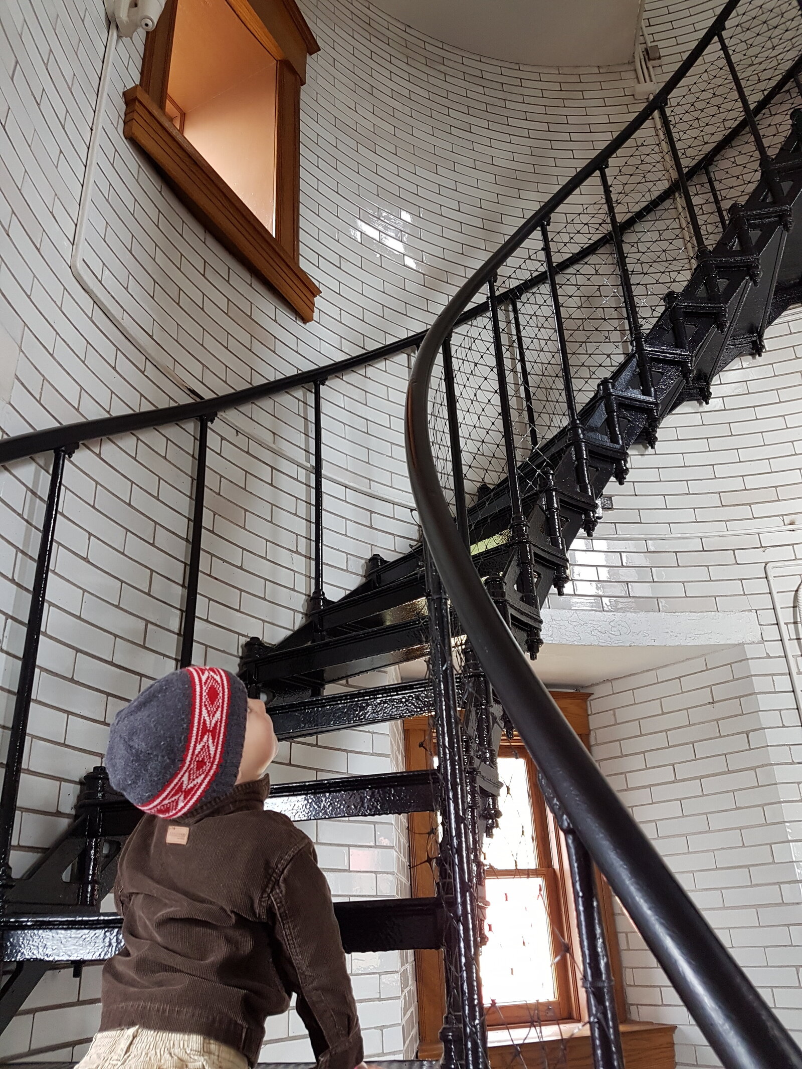 little boy looking up large spiral staircase with wonder