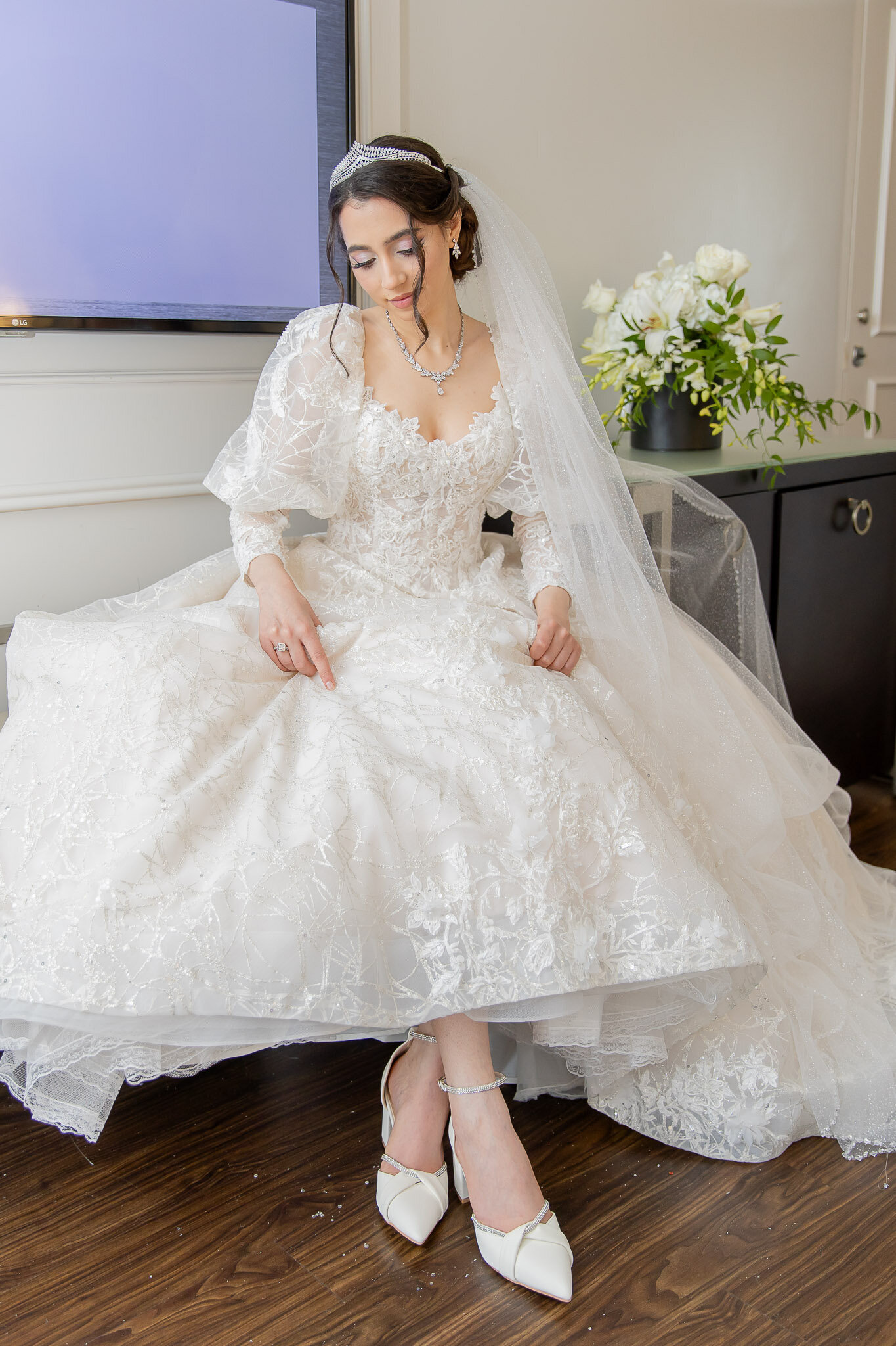A woman wears a vintage wedding dress on her wedding day with lots of lace and puffy sleeves.