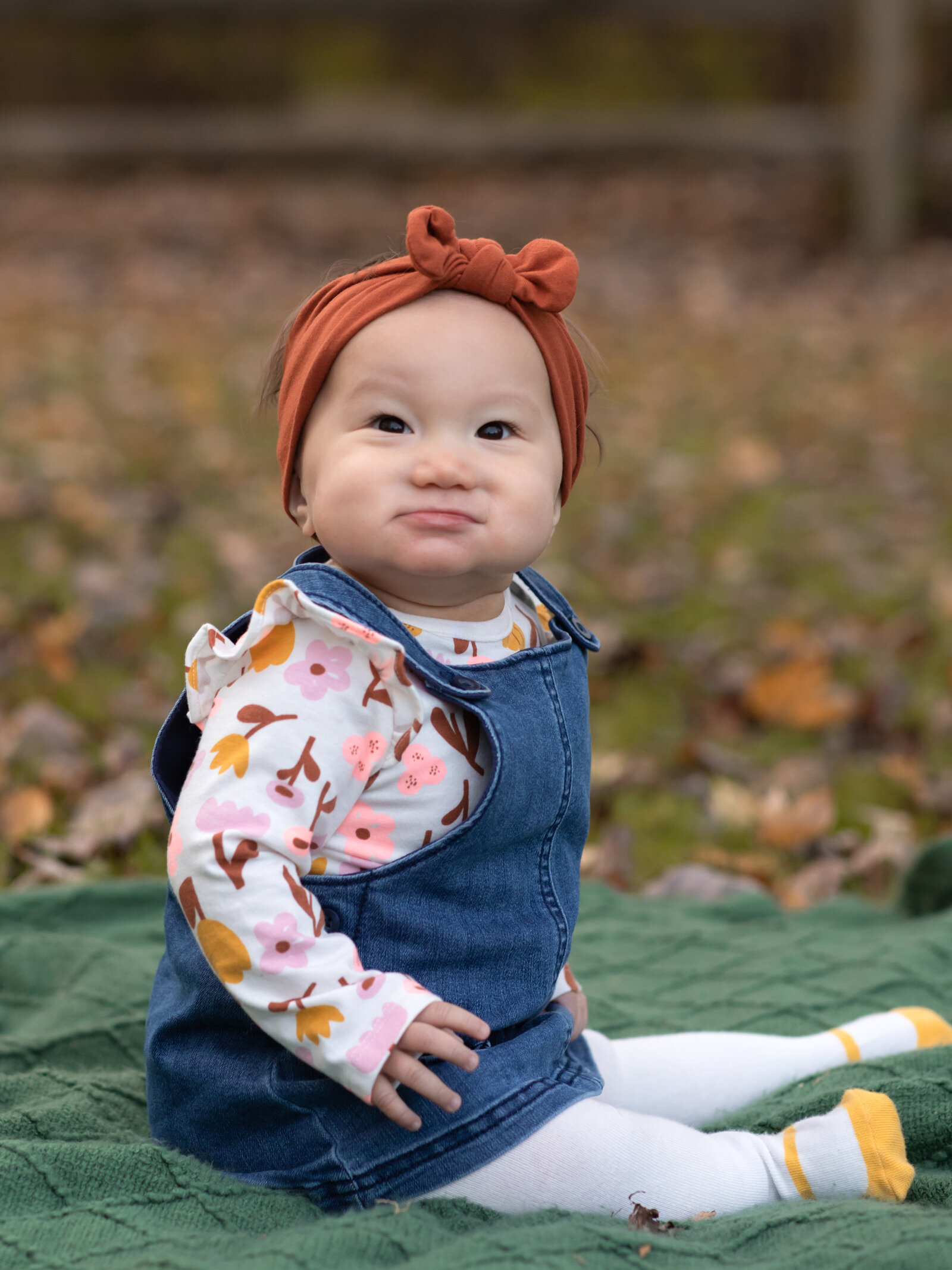 baby girl sitting on blanket for photos in park