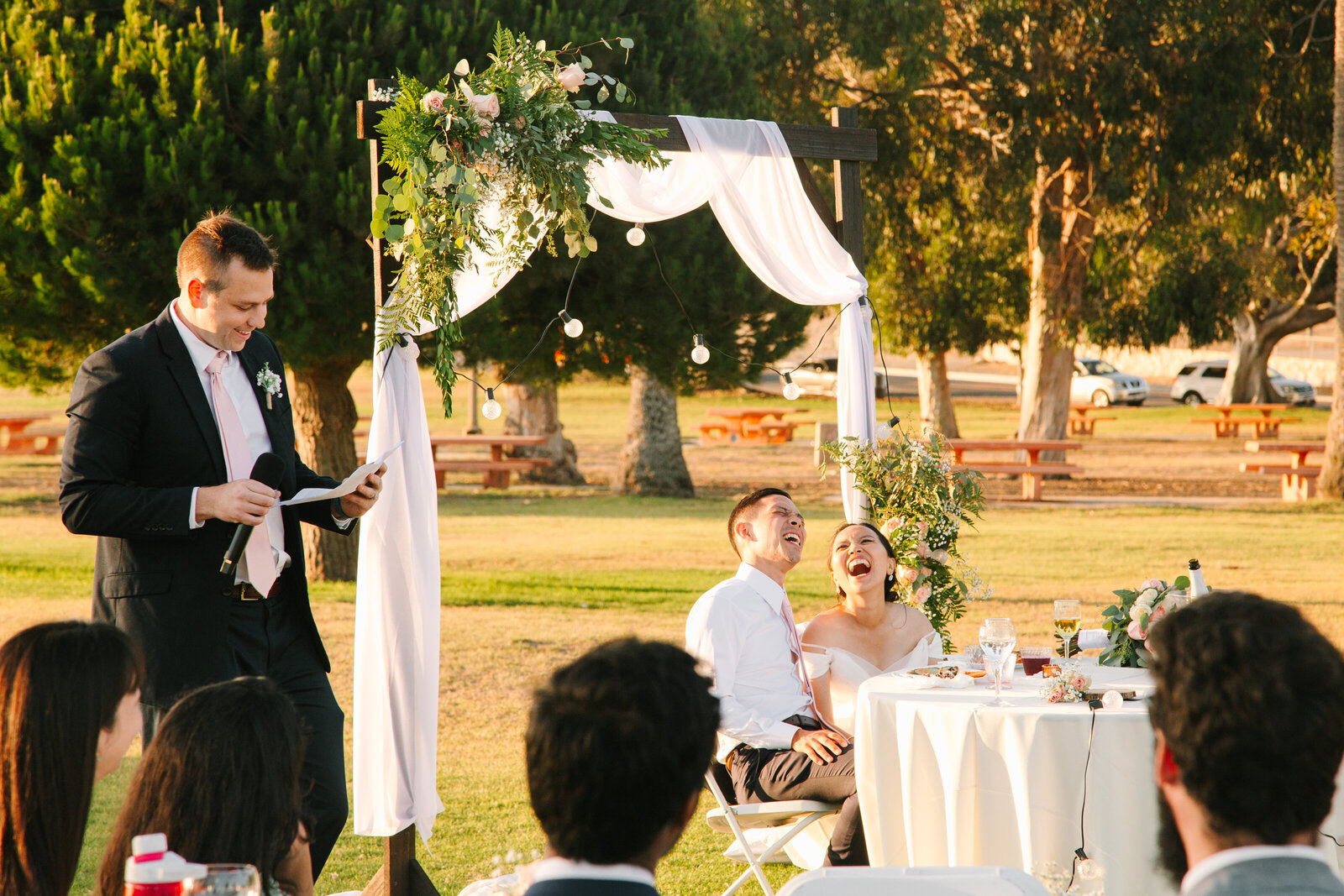 A groomsman gives a speech to the groom at a wedding reception.