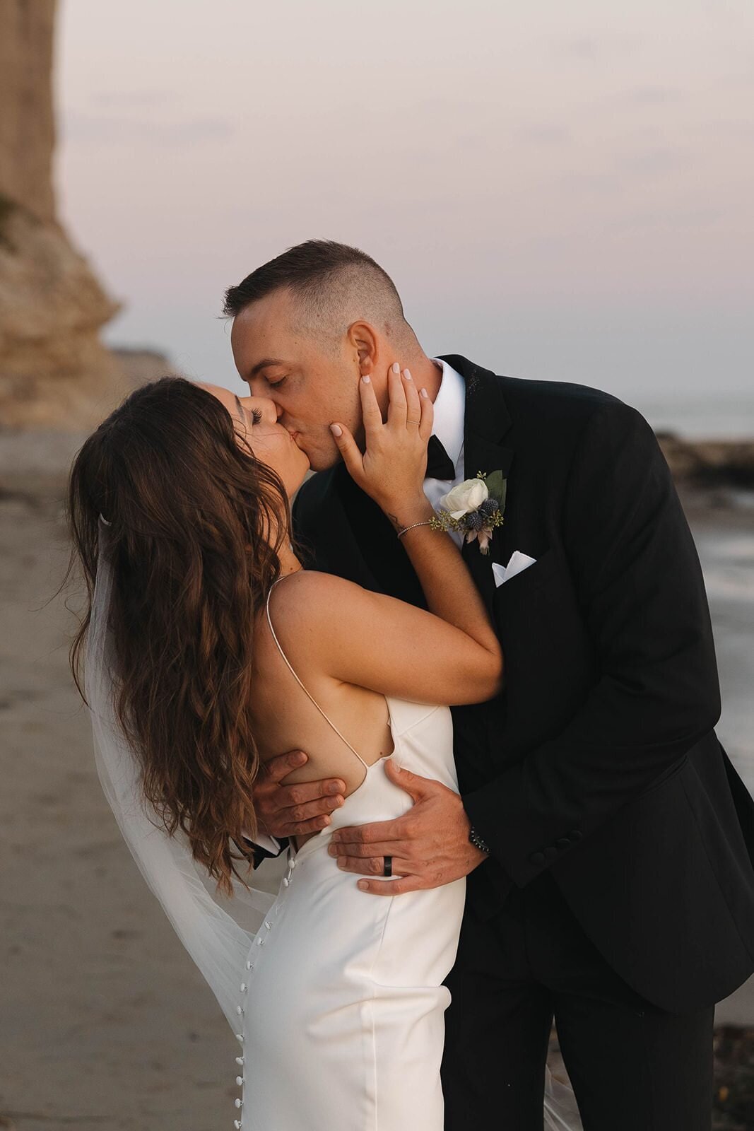 Bride and groom kissing by the bluffs at sunset