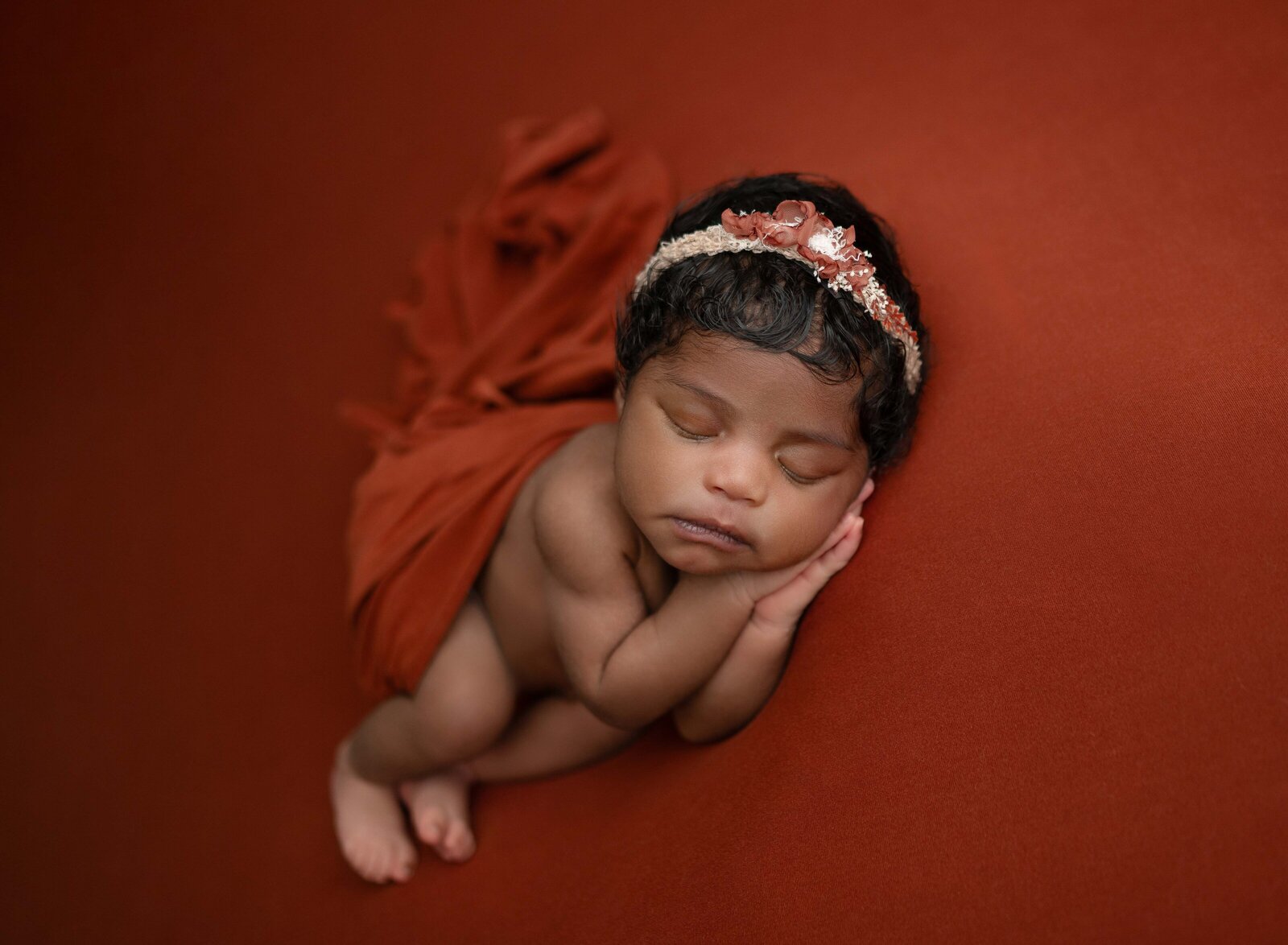 Baby girl sleeping with hands under cheek on rust backdrop. Newborn Photography in Marietta GA by Jenni Nikki Photography.