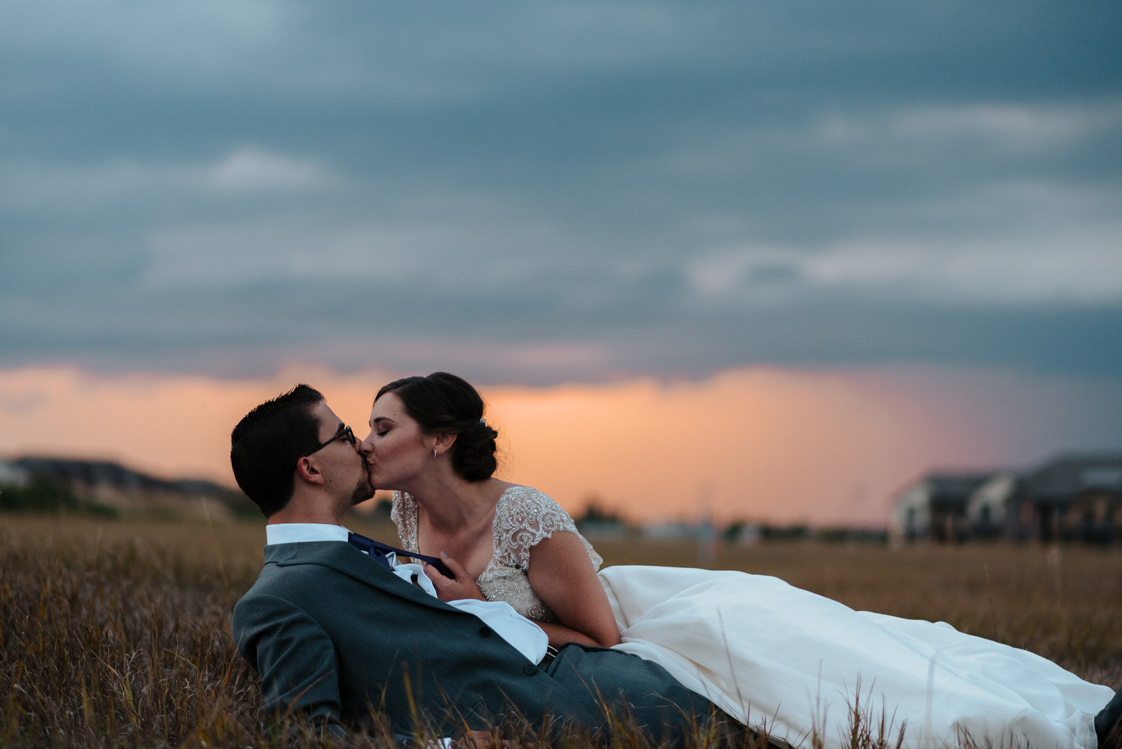 bride and groom kissing in a field at their wedding