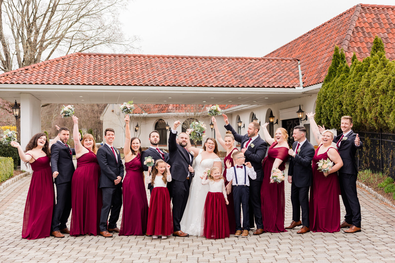 Full wedding party cheering and celebrating together during portraits at Perona Farms wedding venue
