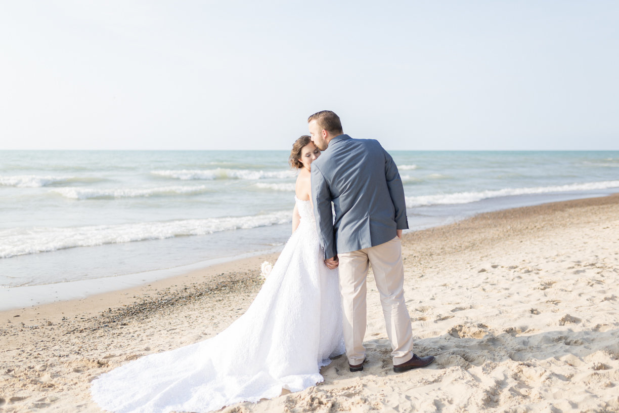 Groom kisses bride's forehead on beachfront- Indiana Dunes