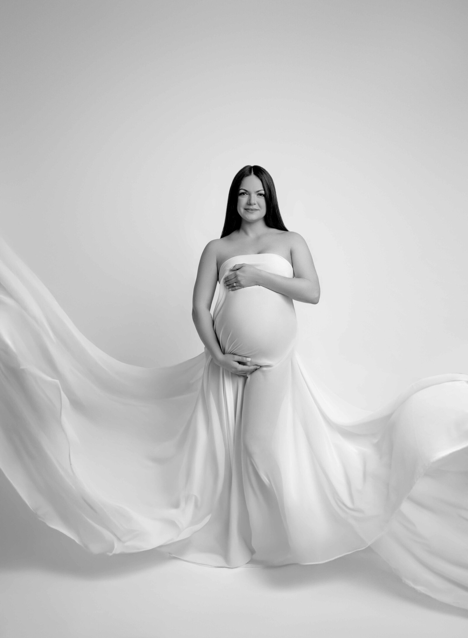 Mom holding belly and white drape tossed in air. Photo taken by Atlanta Maternity Photographer- Jenni Nikki in Woodstock, GA.
