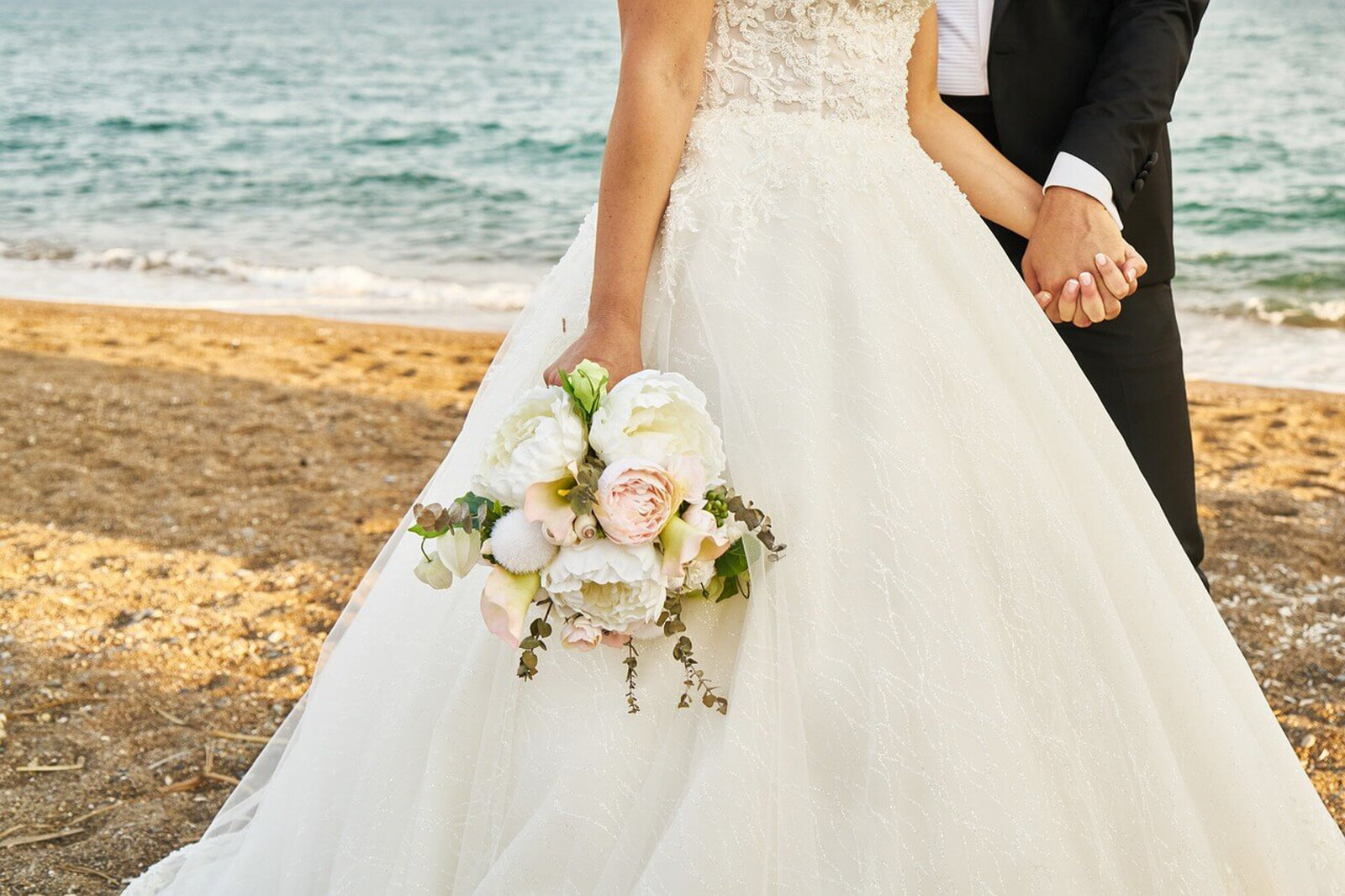 Bride and groom holding hands on the seashore