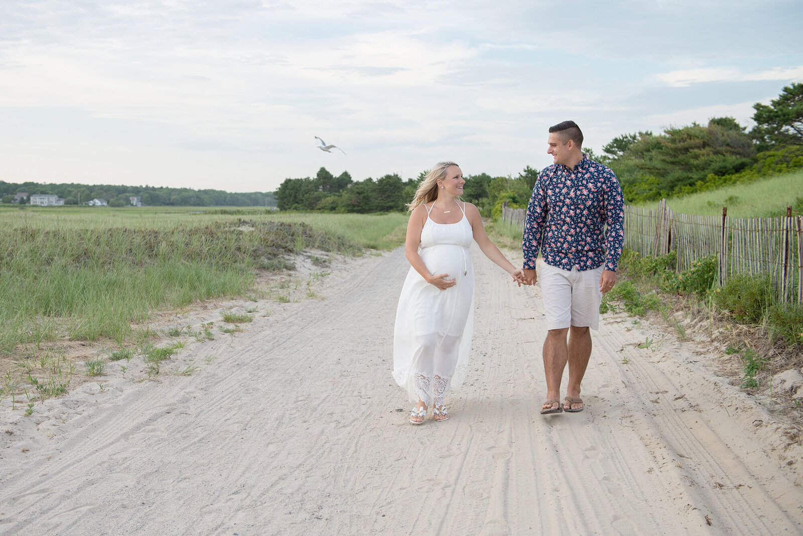 Pregnant couple holding hands walking in Ogunquit Maine