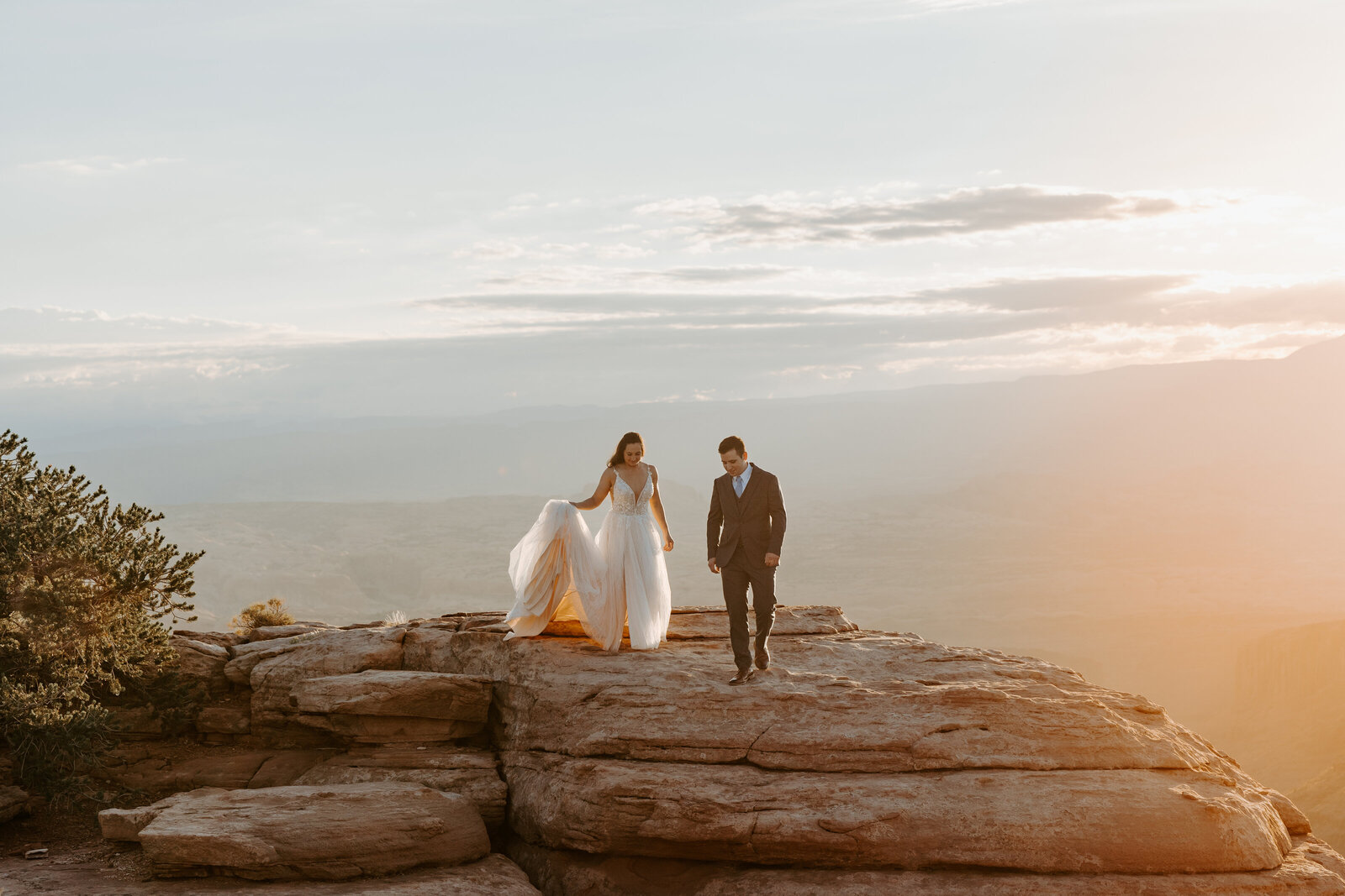 Bride and groom walking on sandstone rocks in Canyonlands National Park at sunrise