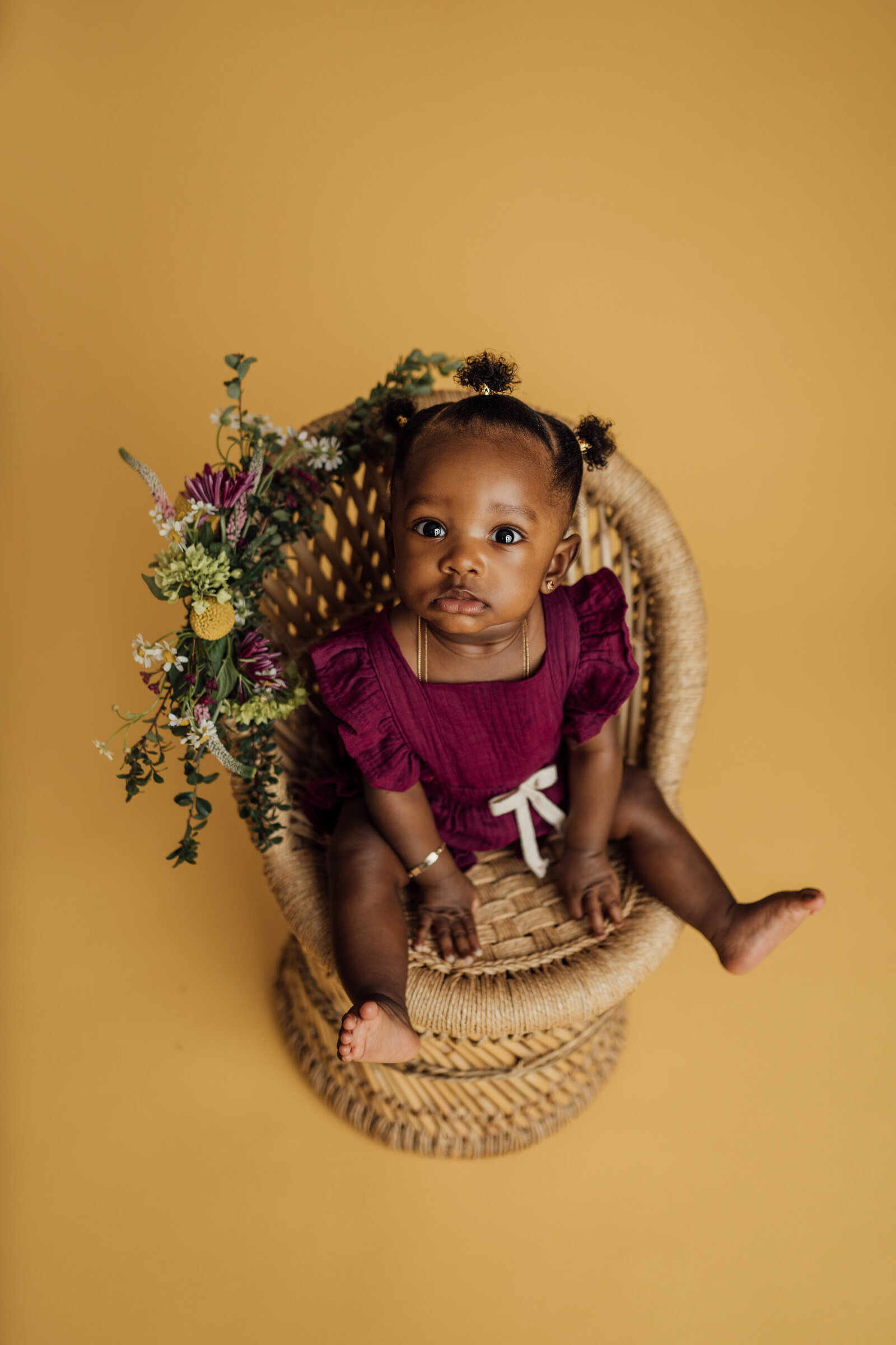 baby girl poses on wicker chair for milestone session in Tampa
