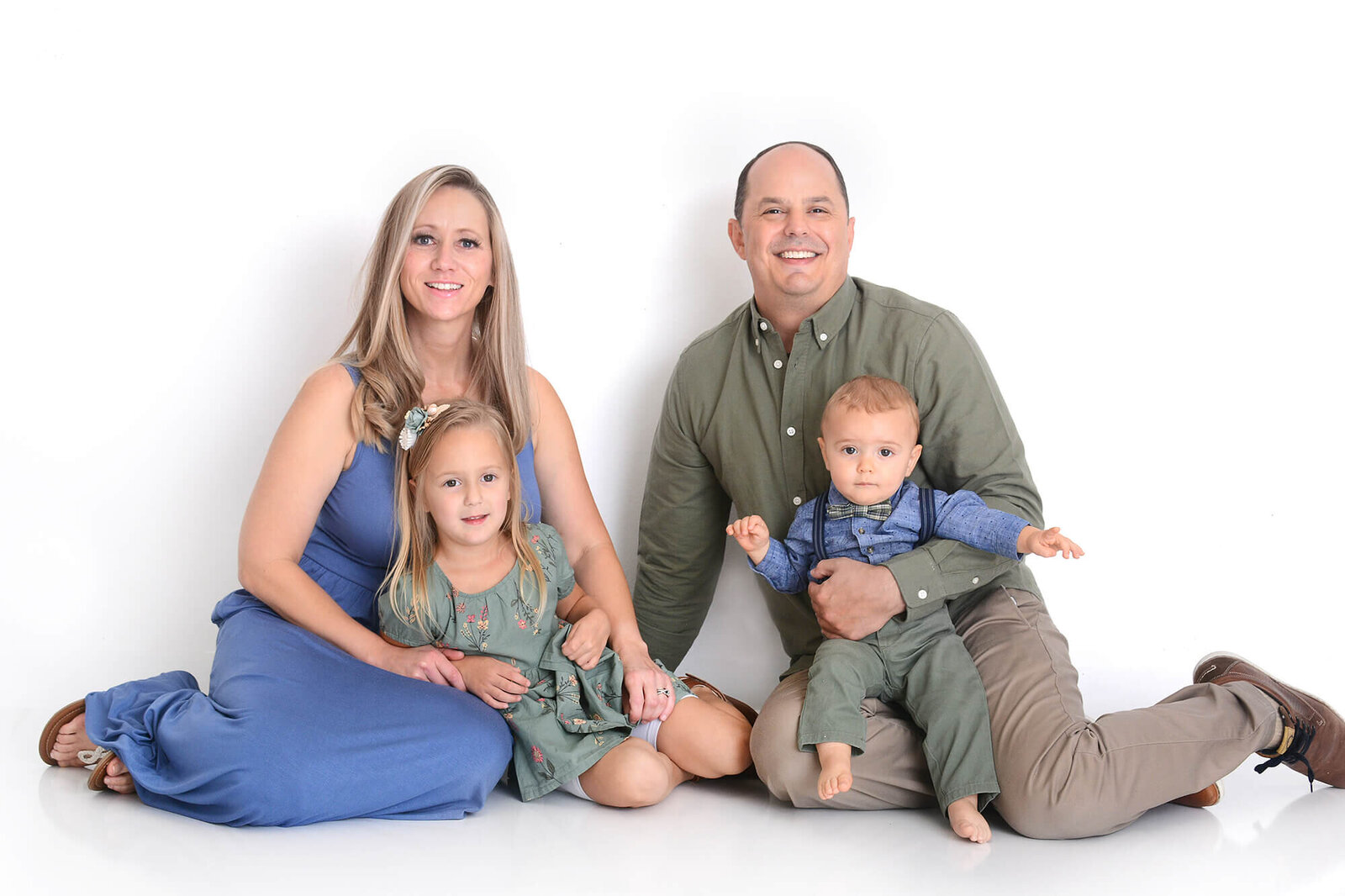 family cuddles up holding their one year old and 6 year old at their families photoshoot