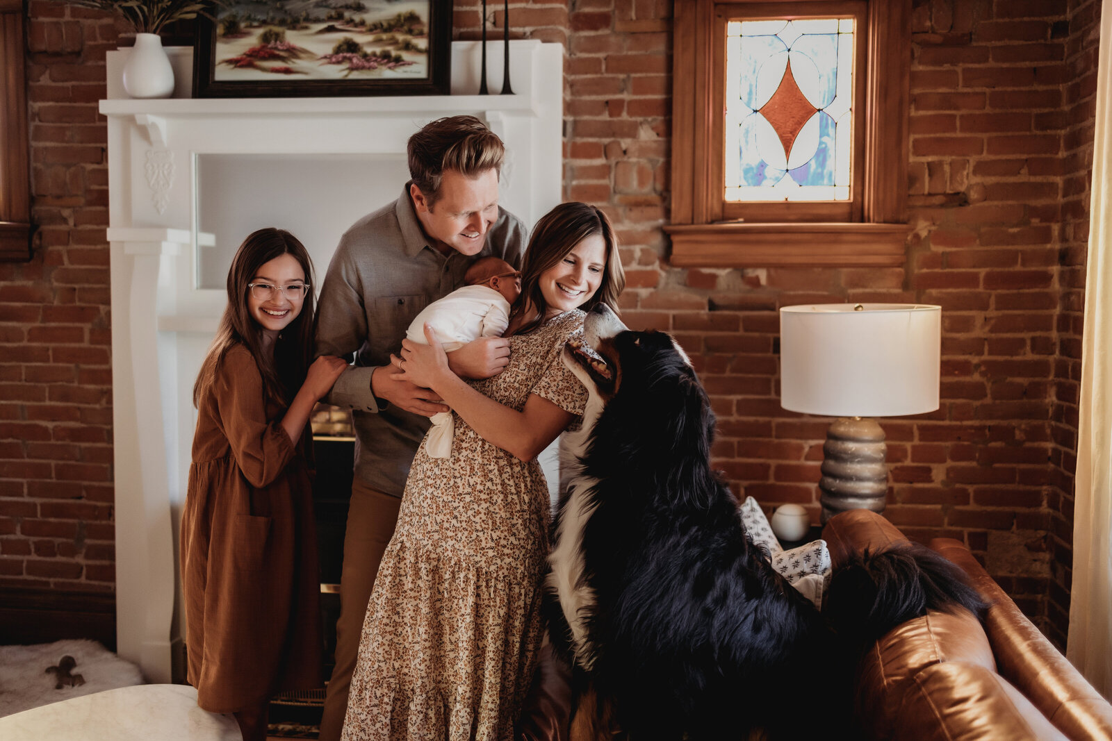 Family of four standing in  brick living room with large dog smiling