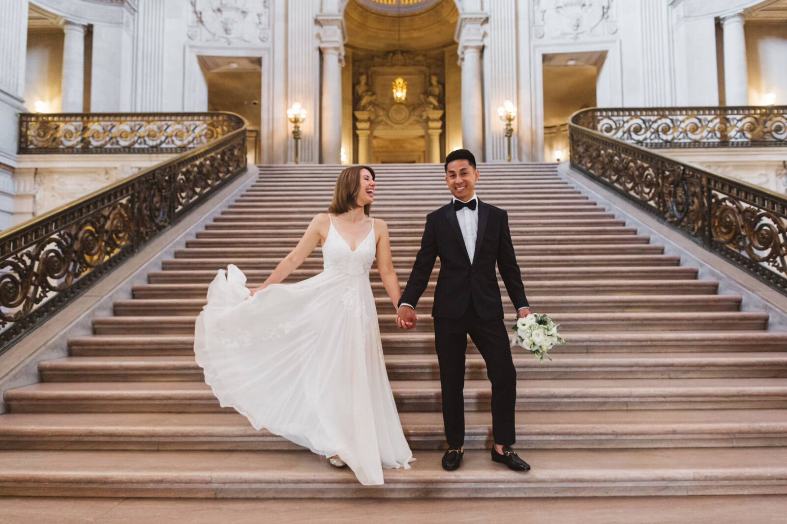 bride swooshing wedding dress dramatically at the foot of the Grand Staircase