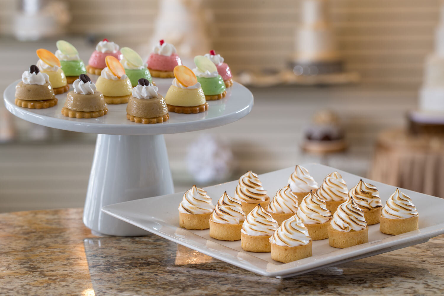 Assorted mini desserts on white serving trays and cake stands