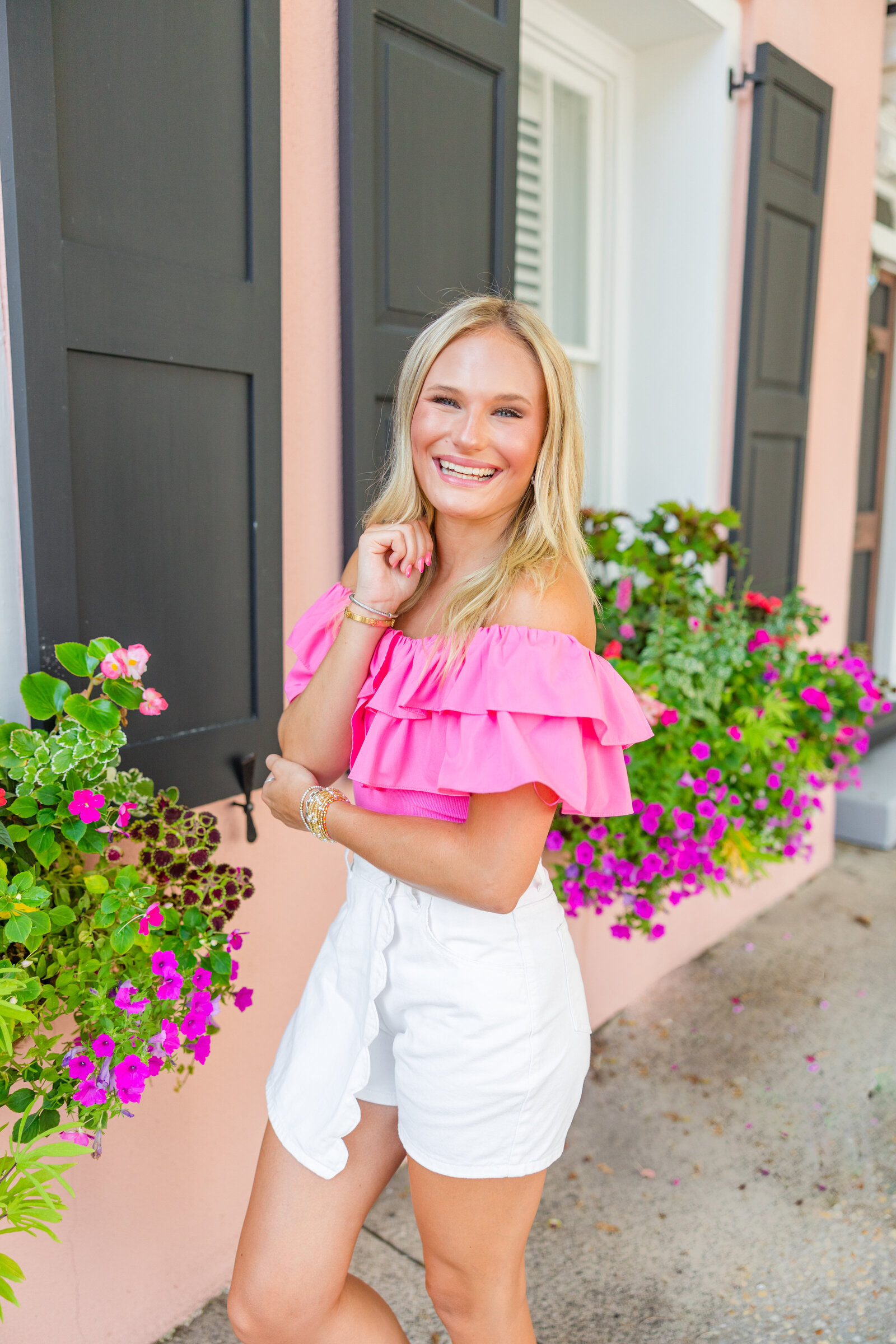 high school senior with pink ruffled blouse and white shorts photographed in downtown Charleston, South Carolina by South Carolina senior portrait photographer