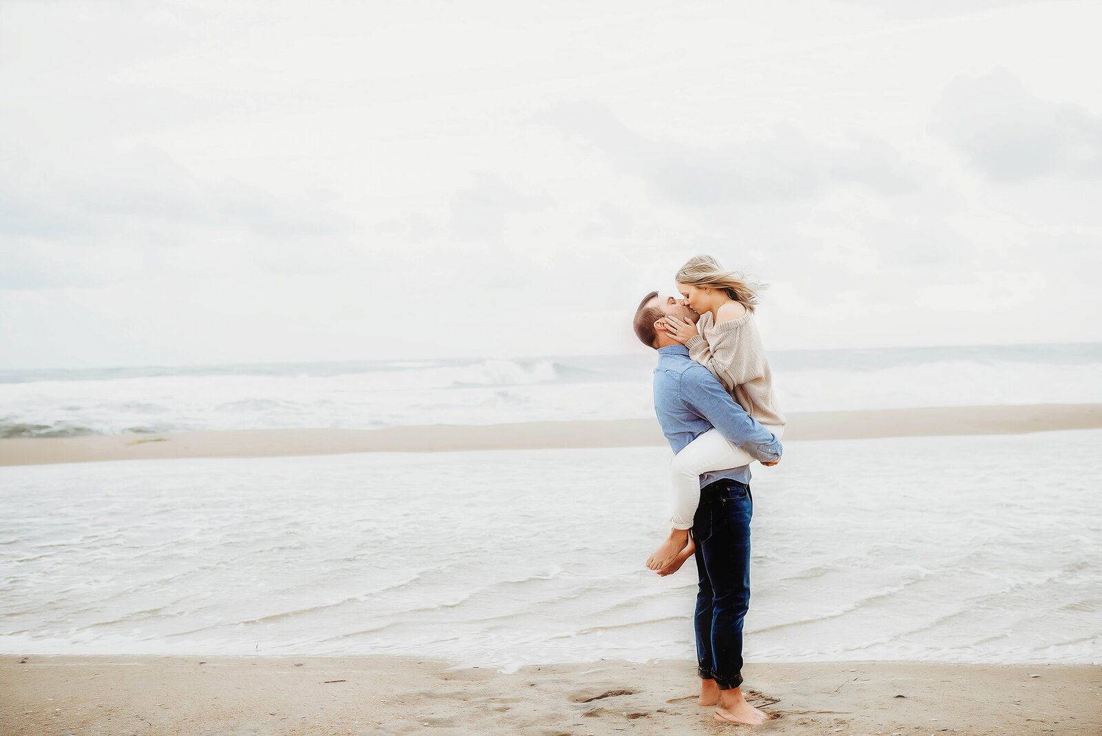 Engaged couple kisses passionately on the beach during a hurricane in the Outer Banks of North Carolina.