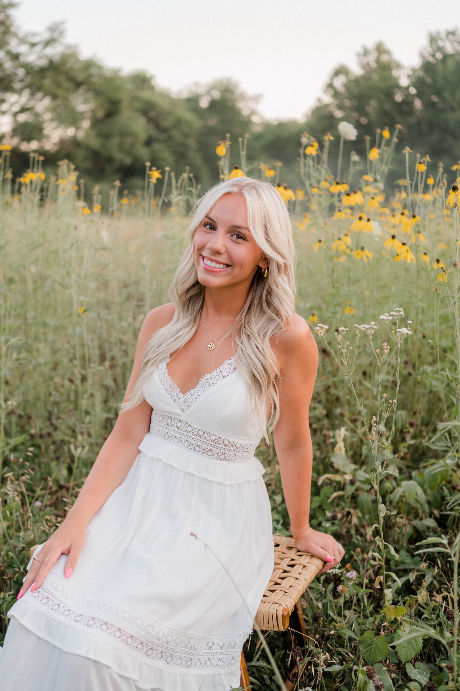 Girl in white dress poses in field with yellow flowers