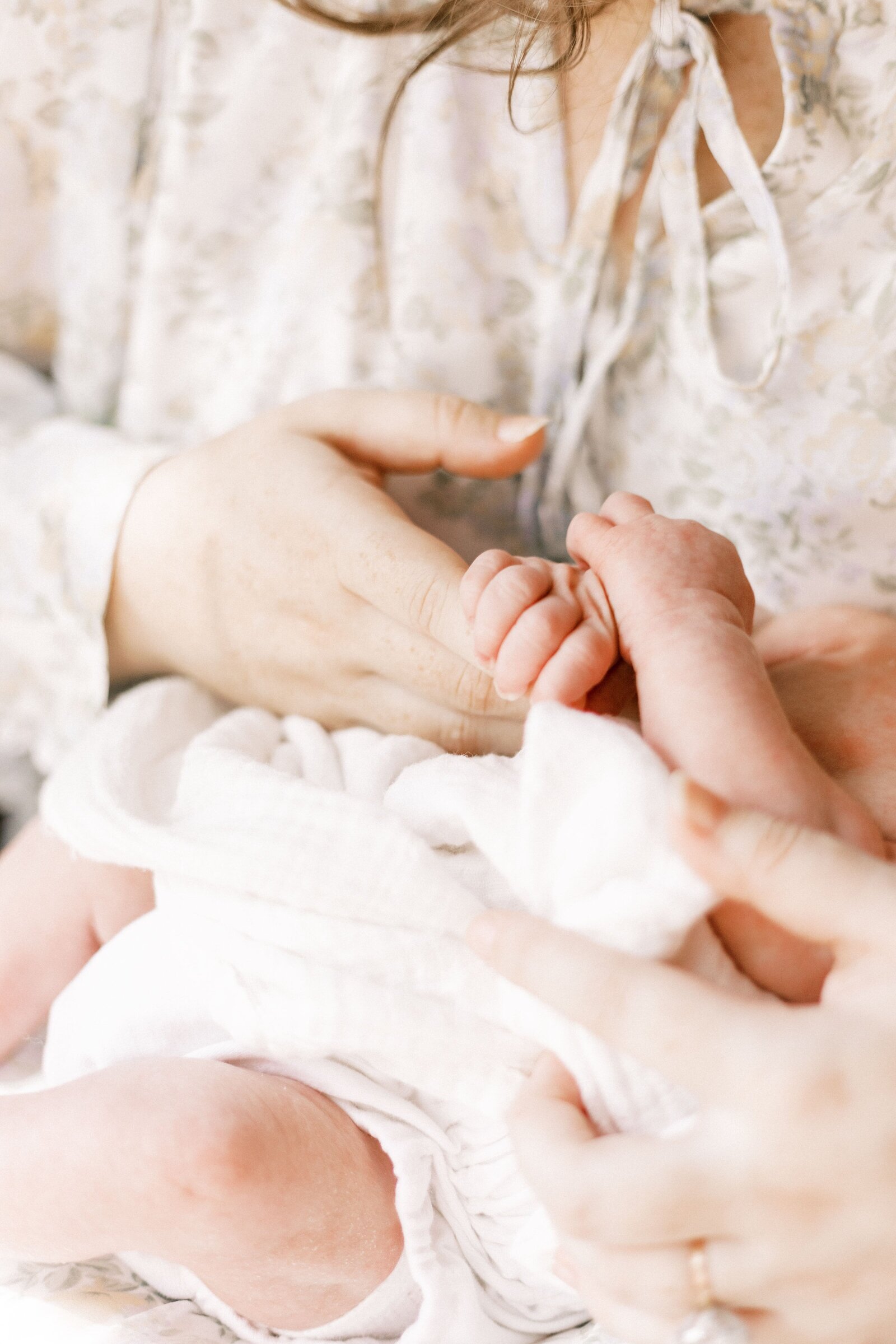 mom holding newborn baby's hand in newborn photos in peoria illinois 