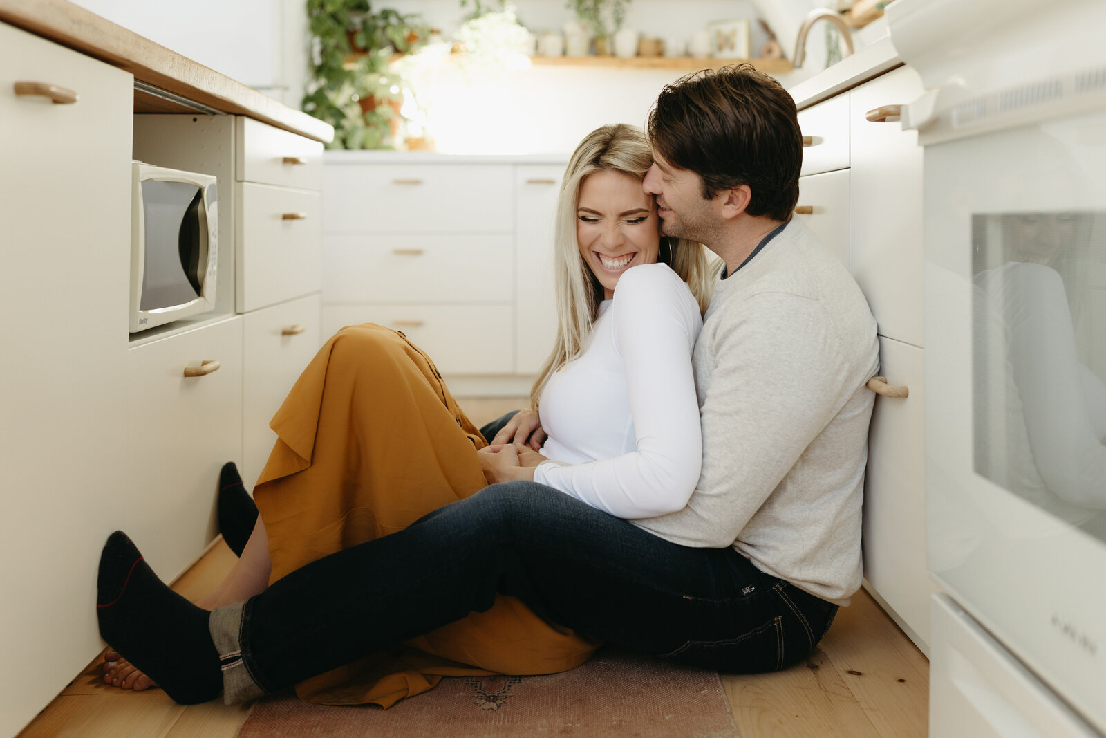 A couple cuddles up on the floor for a cute photo of them at the A-Frame on fletcher, located in Halifax.