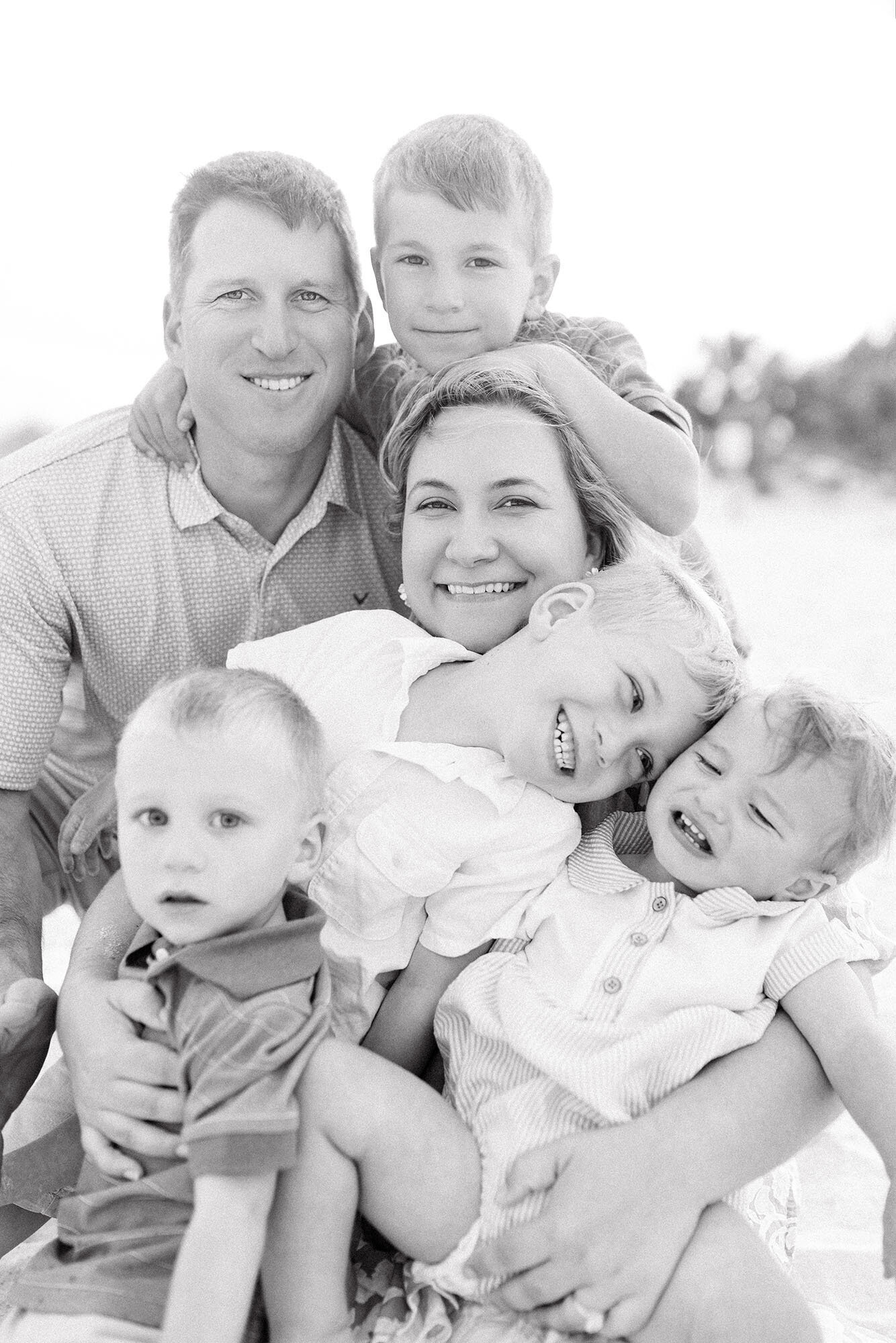 A candid photo of a family of six laughing and looking at the camera 