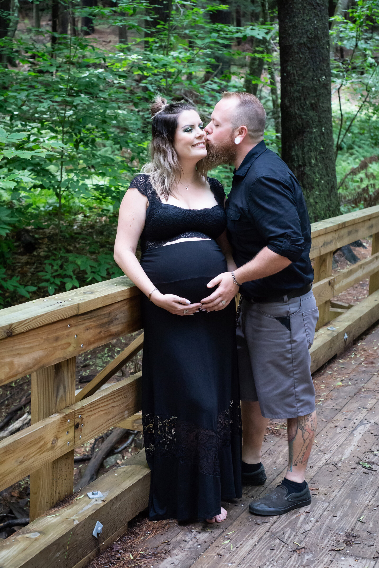 Pregnant couple kissing on bridge in Eliot Maine