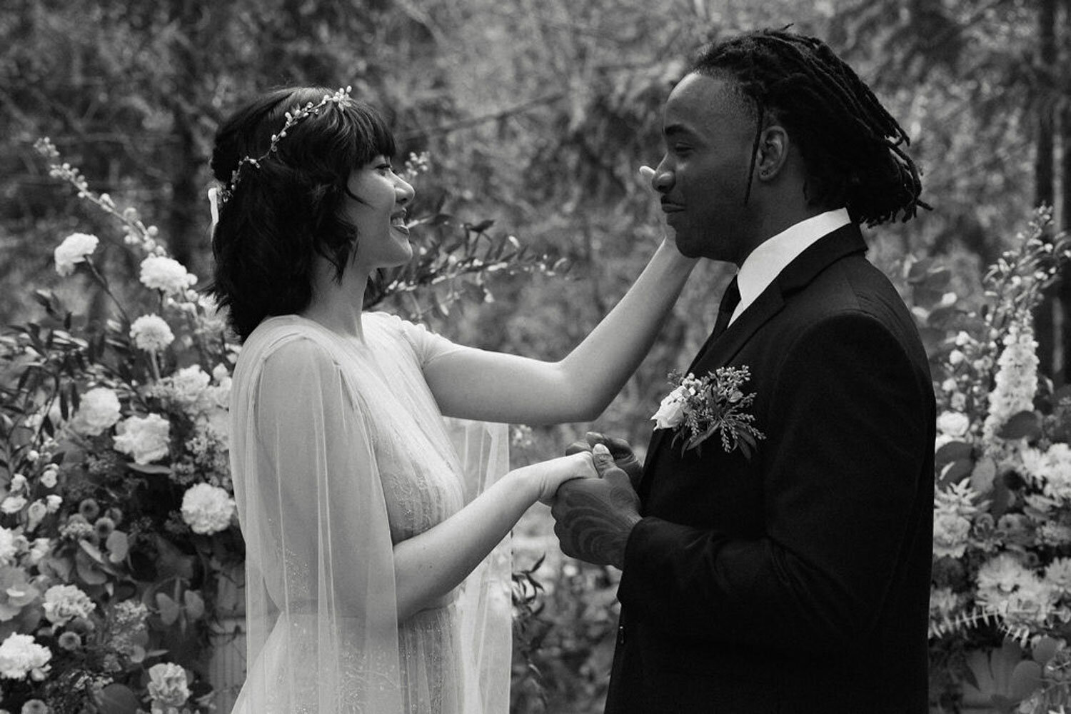 Bride smiling while holding groom’s face during a tender moment