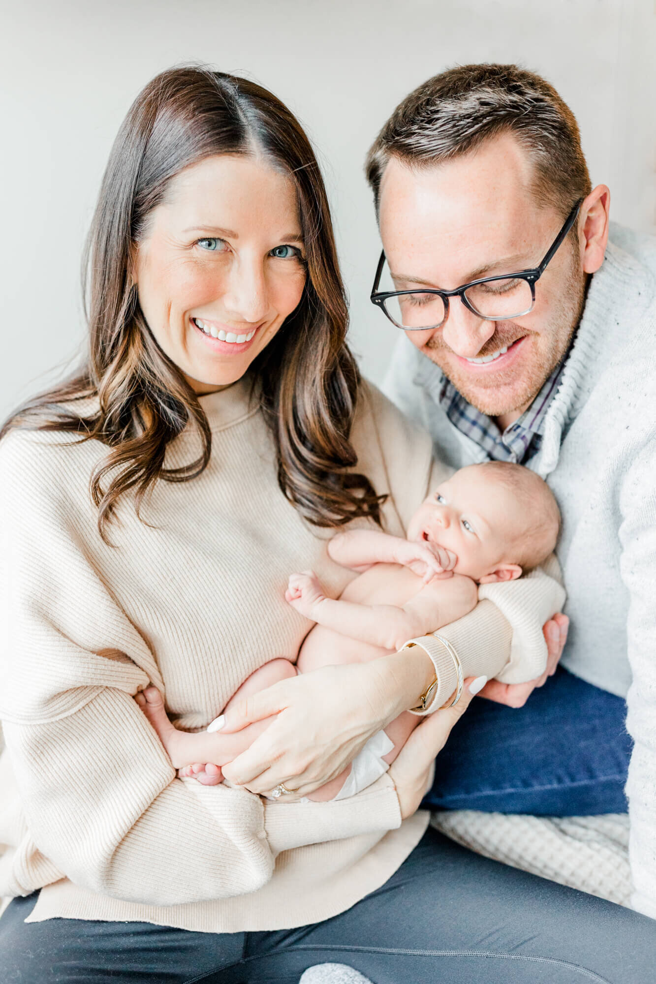 Dad and mom laugh while mom holds their newborn