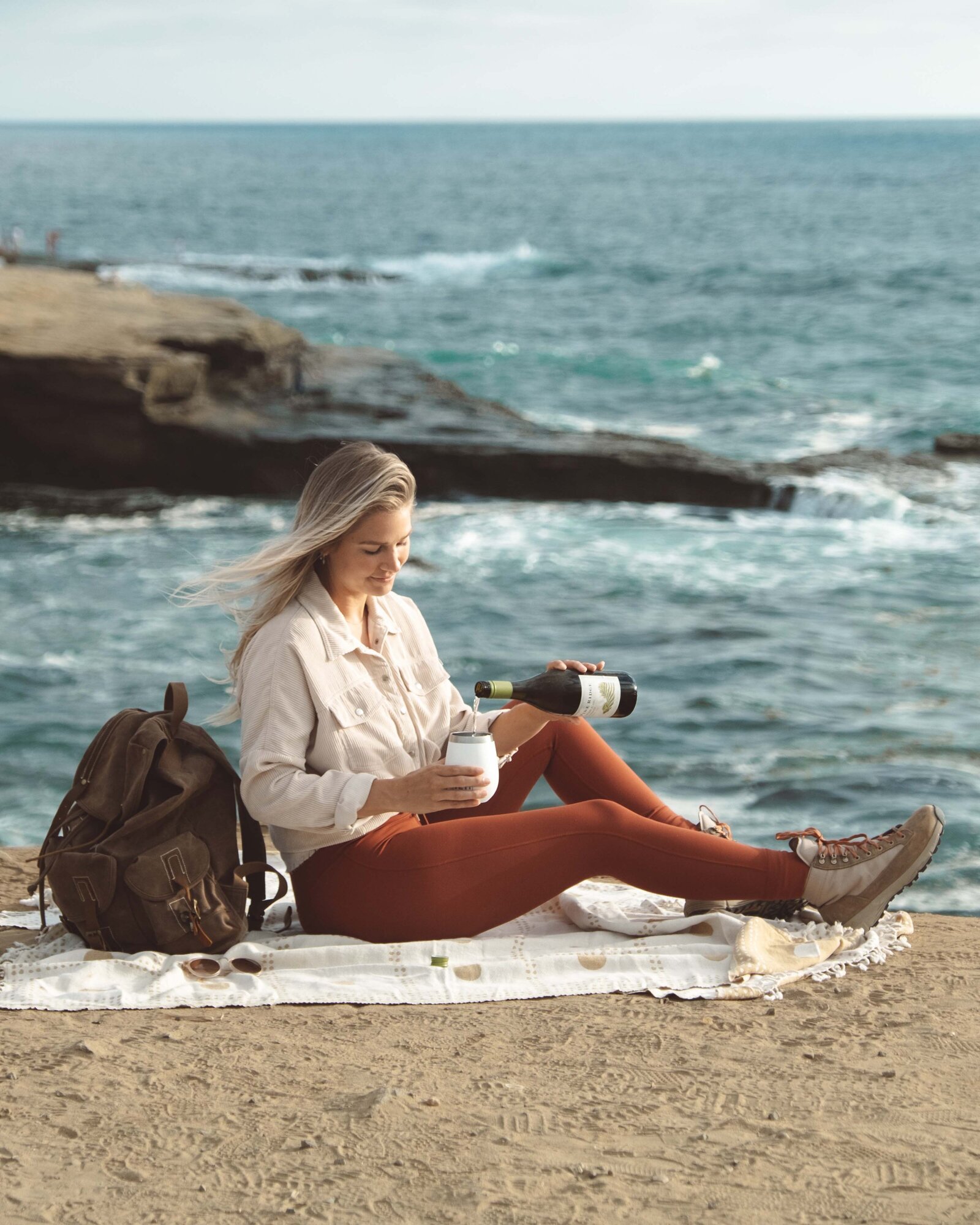 Girl at sunset cliffs in san diego with backpack for wine brand styled product photography for san diego business