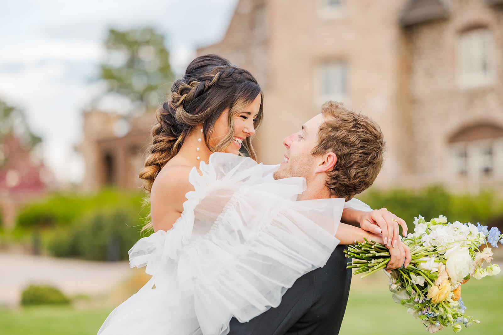 Groom holding his bride in his arms during their beautiful wedding at the Highlands Ranch Mansion in Colorado.