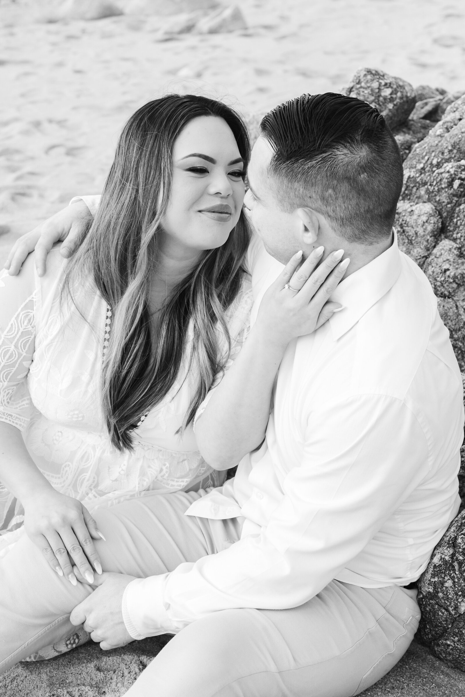 An engaged man and woman take photos on the beach in Pacific Grove, Monterey, California near Big Sur.
