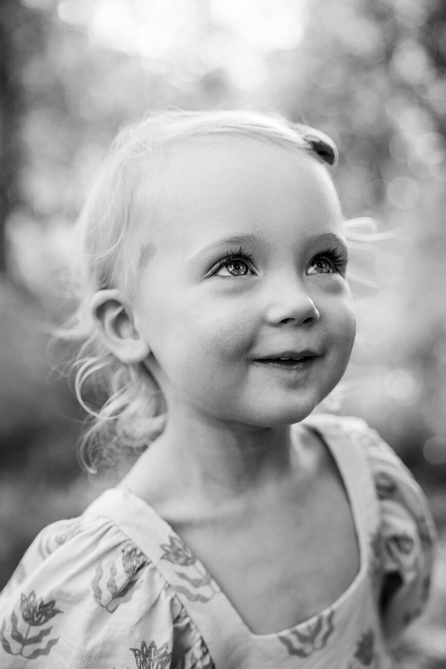 black and white portrait of toddler girl smiling up at sky