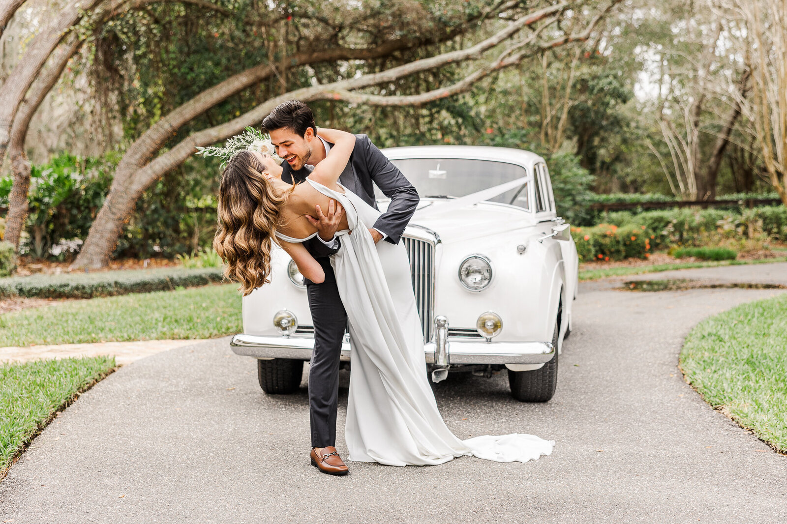 a bride and groom almost kiss as they stand in front of a classic car