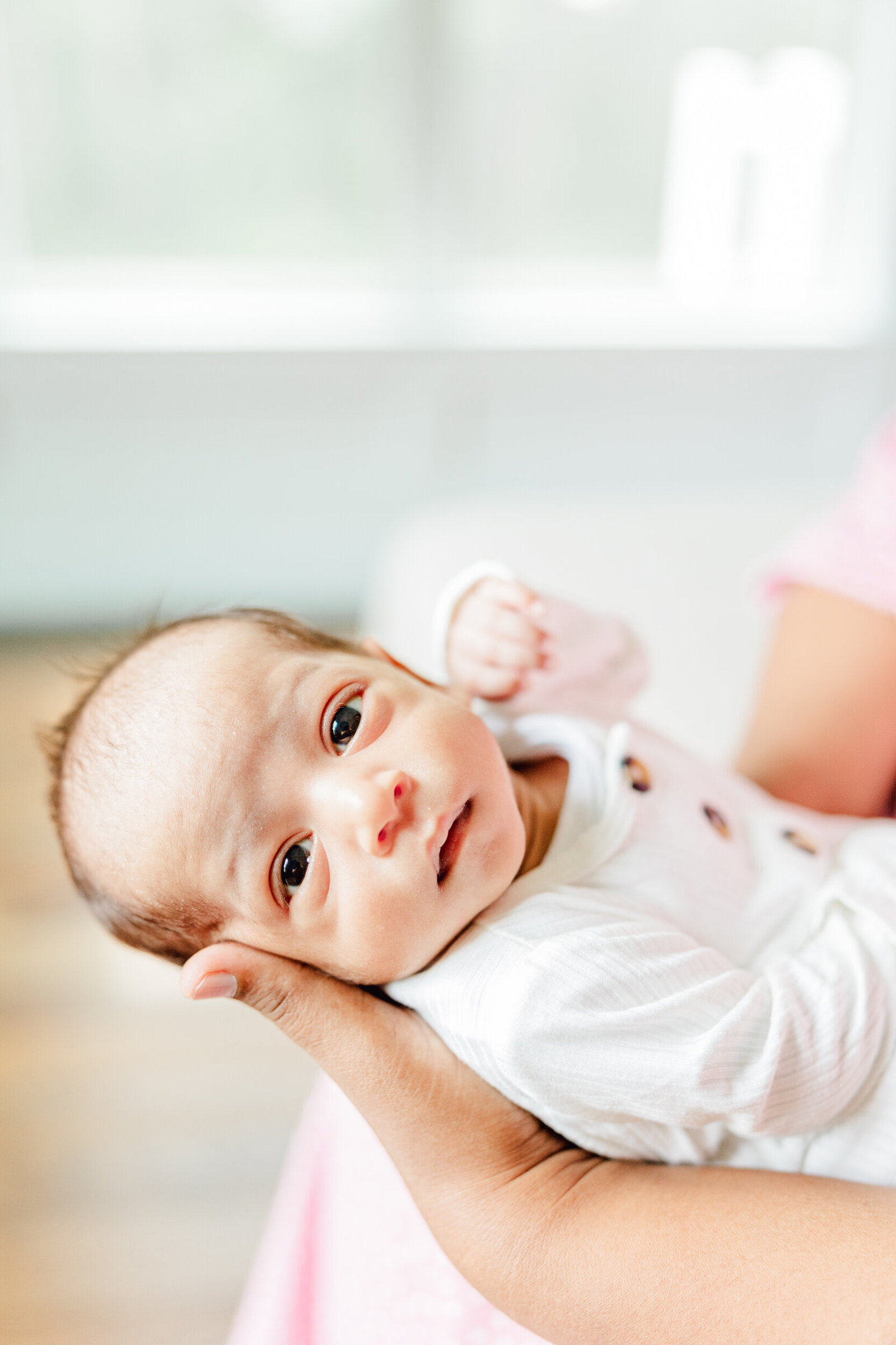 Newborn boy in mom's arms looks toward the viewer