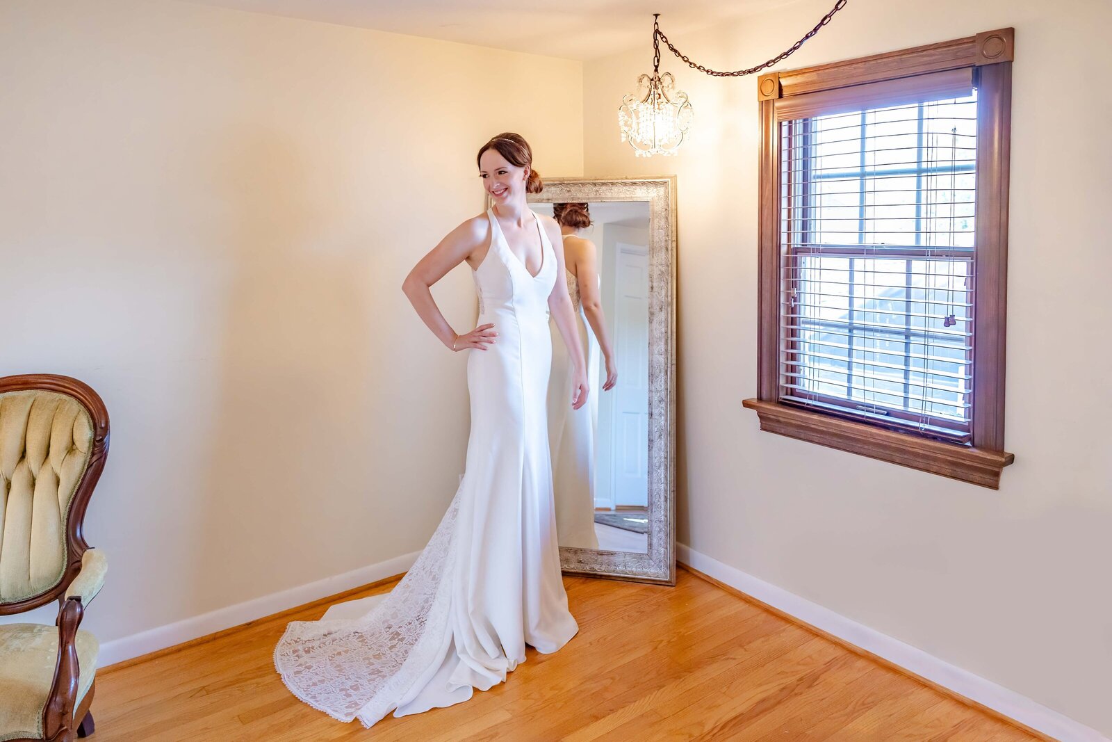 A glowing bride poses in a sleek, elegant wedding gown in a rustic Farmhouse venue bridal suite with vintage decor and natural light, captured in Wilmington, Delaware.