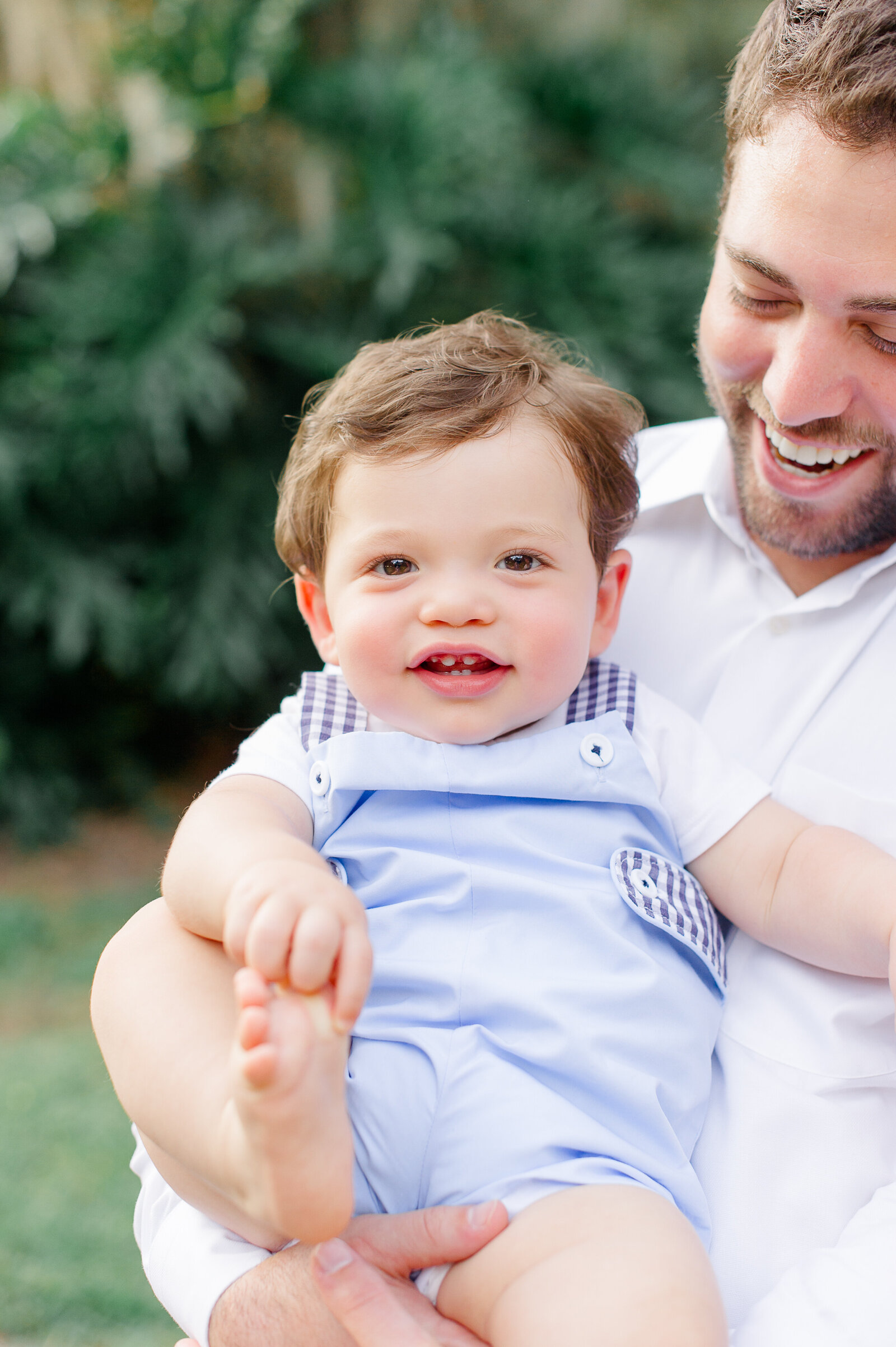 Close up of dad holding young boy wearing blue smiling at the camera