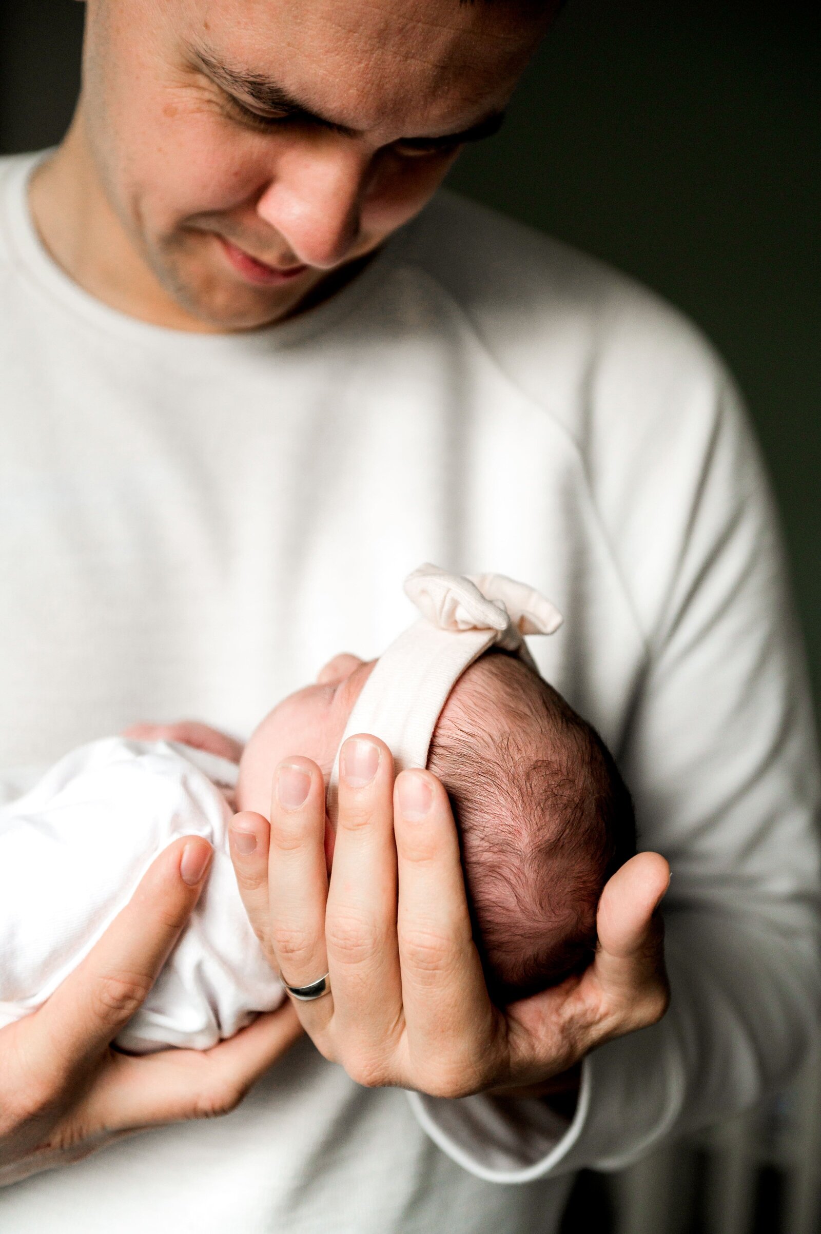new dad holding a baby girl in his hands during a newborn photography session in Baltimore  Marland