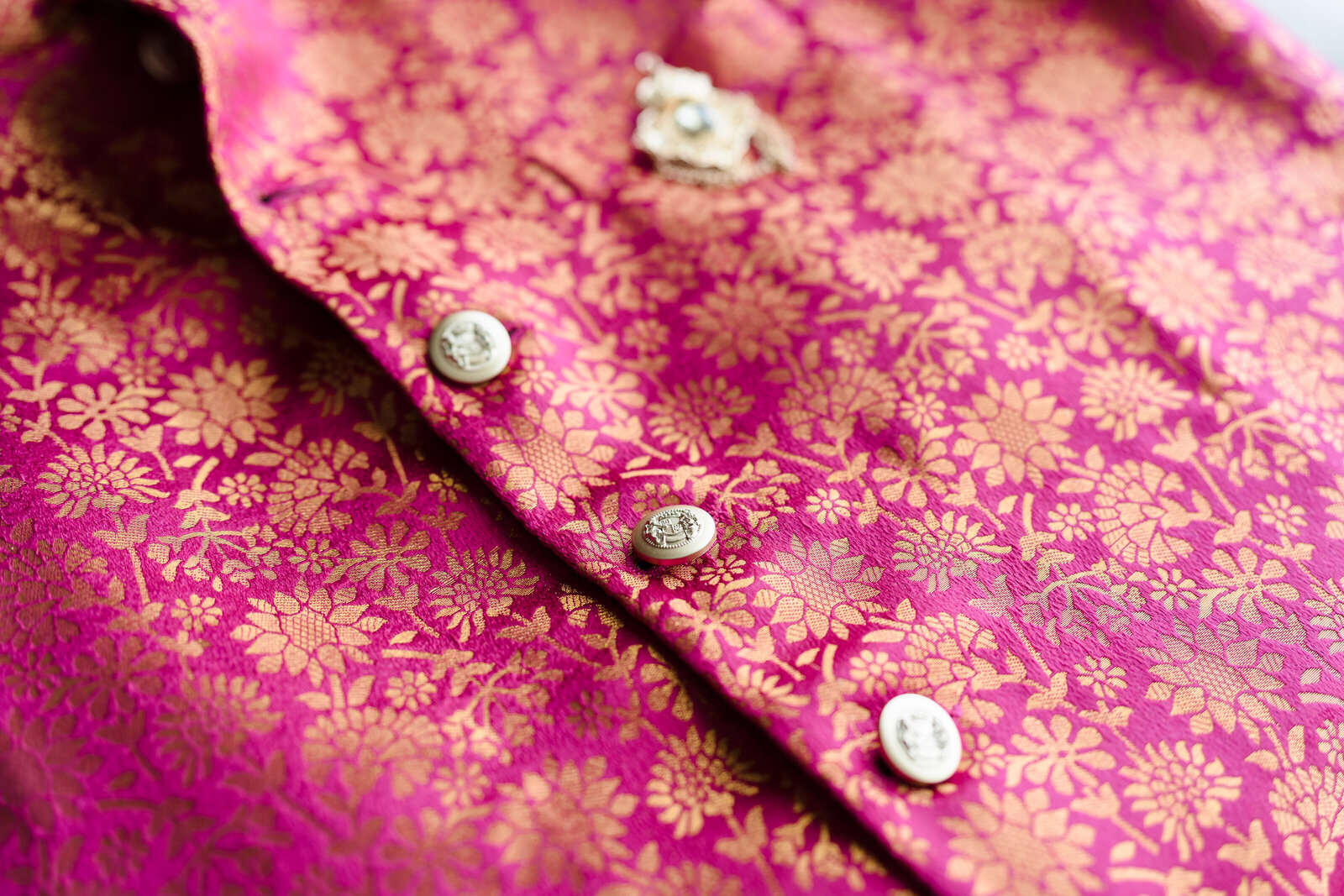 Detail photo of a pink groom's vest with intricate gold florals at an Indian wedding