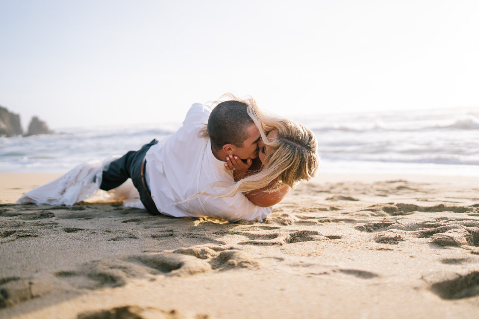 Sacramento Wedding Photographer captures couple rolling in sand after beach wedding