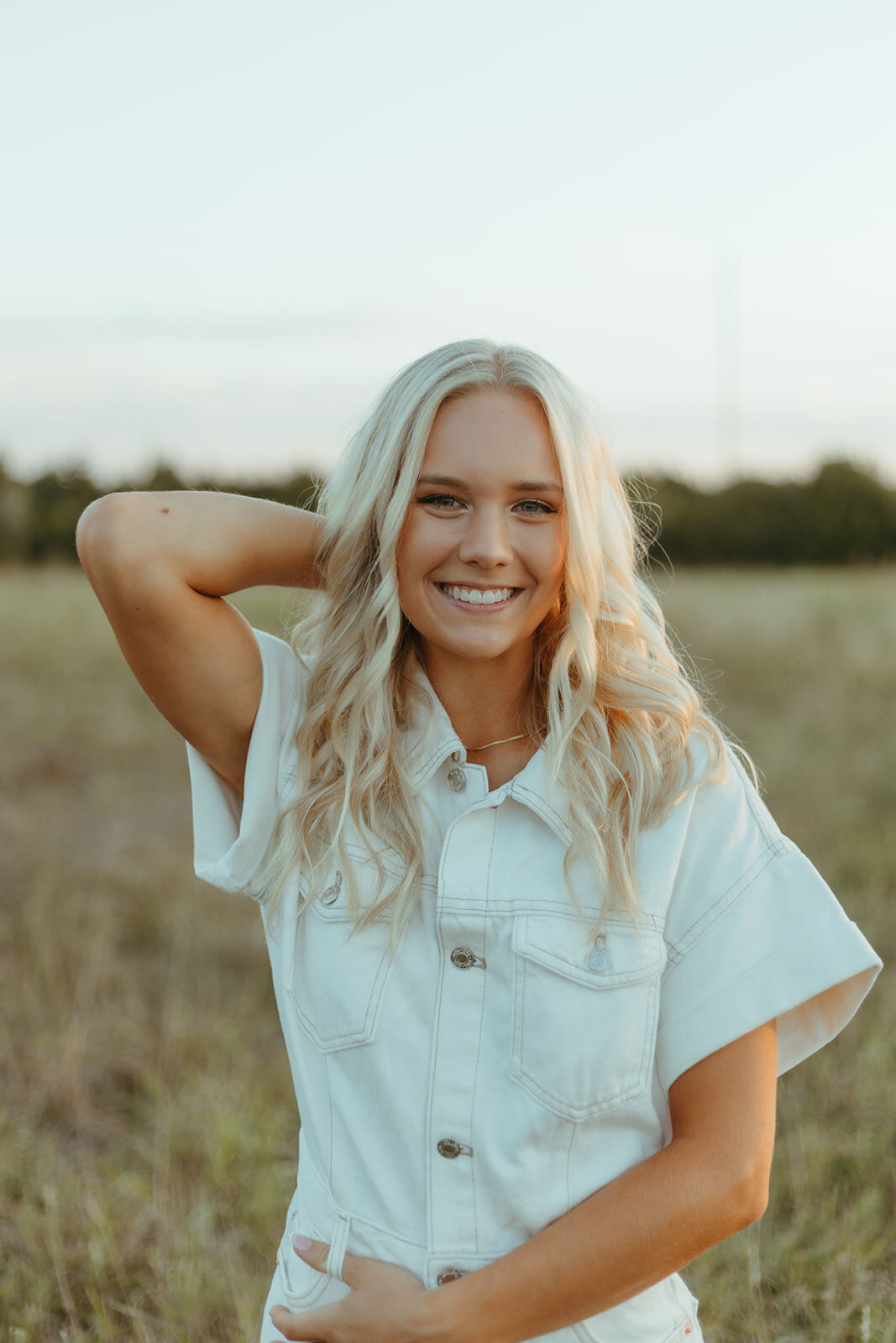 high school senior poses in a country field for senior photos with ashley cole photography