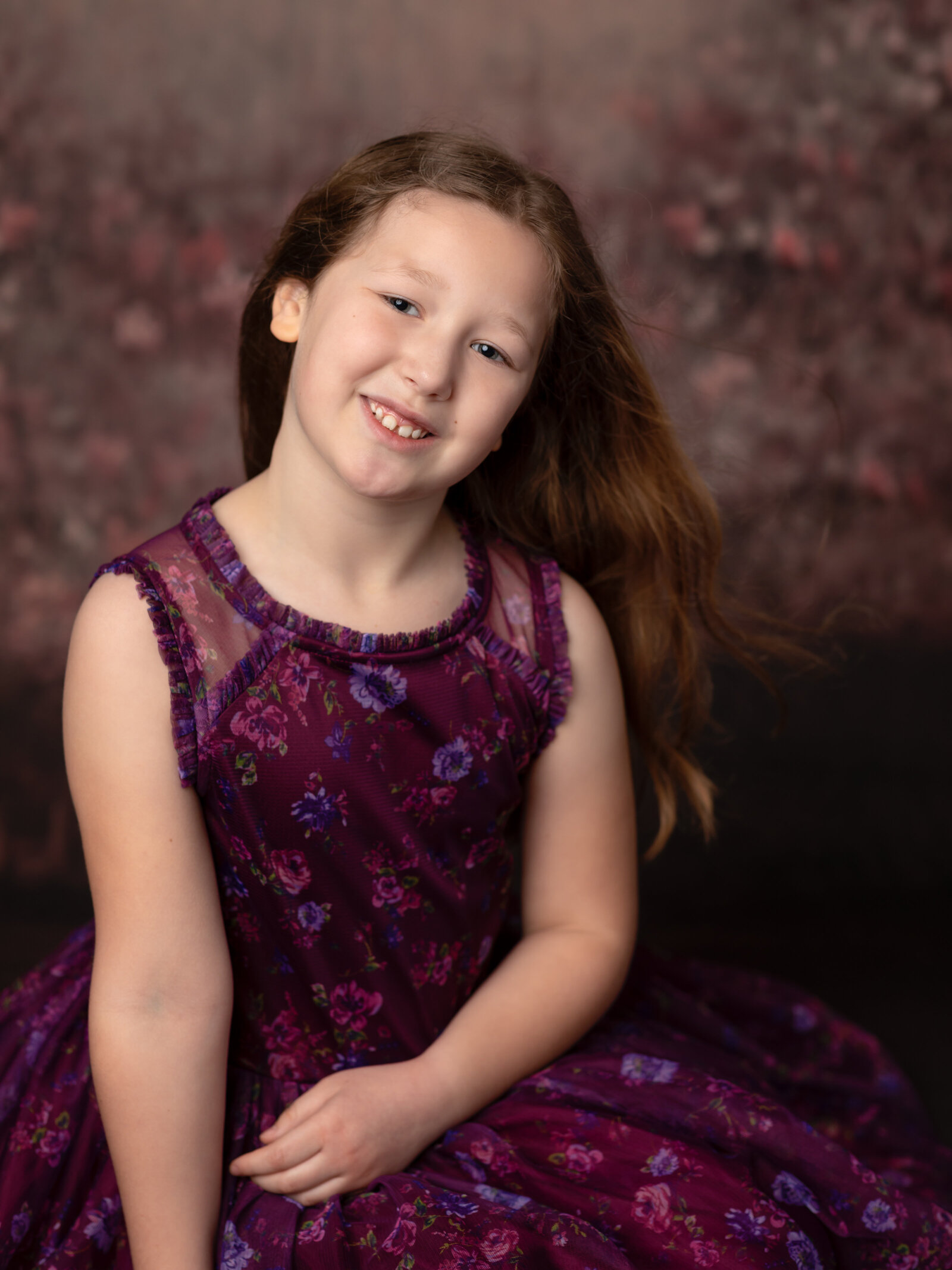 girl in purple dress with floral backdrop for studio birthday photoshoot